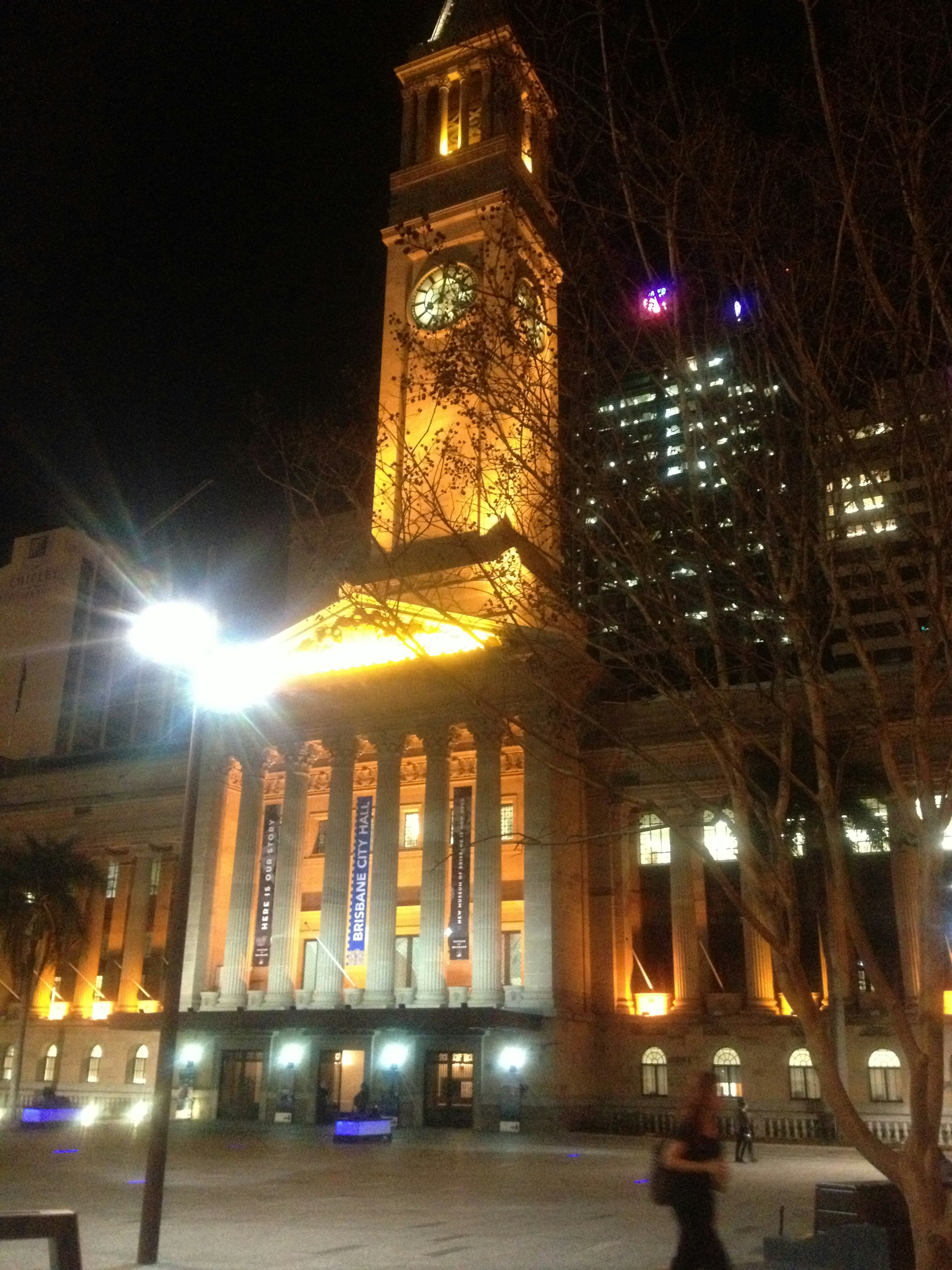 Balai Kota Brisbane yang diterangi di malam hari dengan menara jam