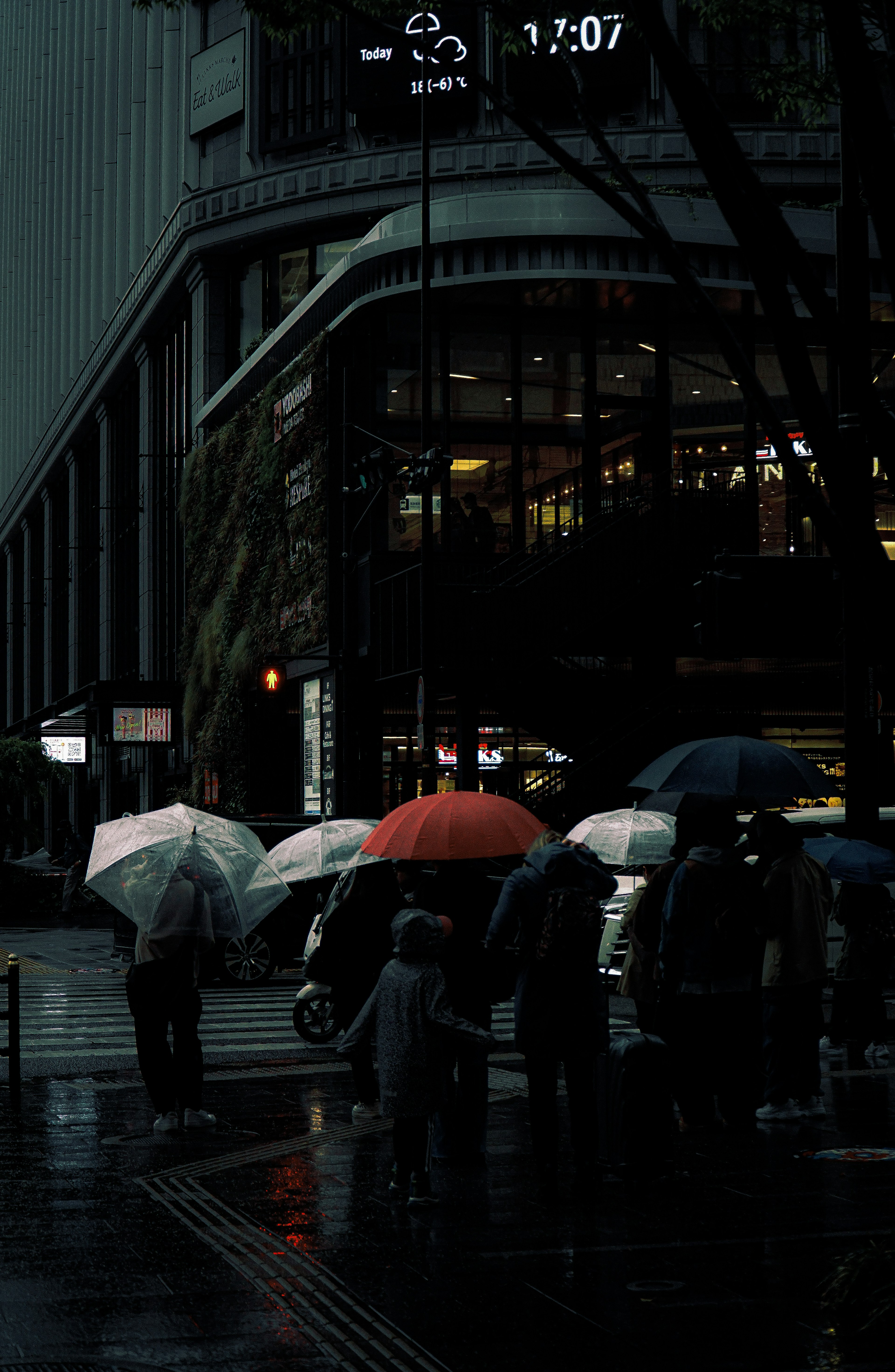 Silhouettes of people with umbrellas in the rain and a dark cityscape