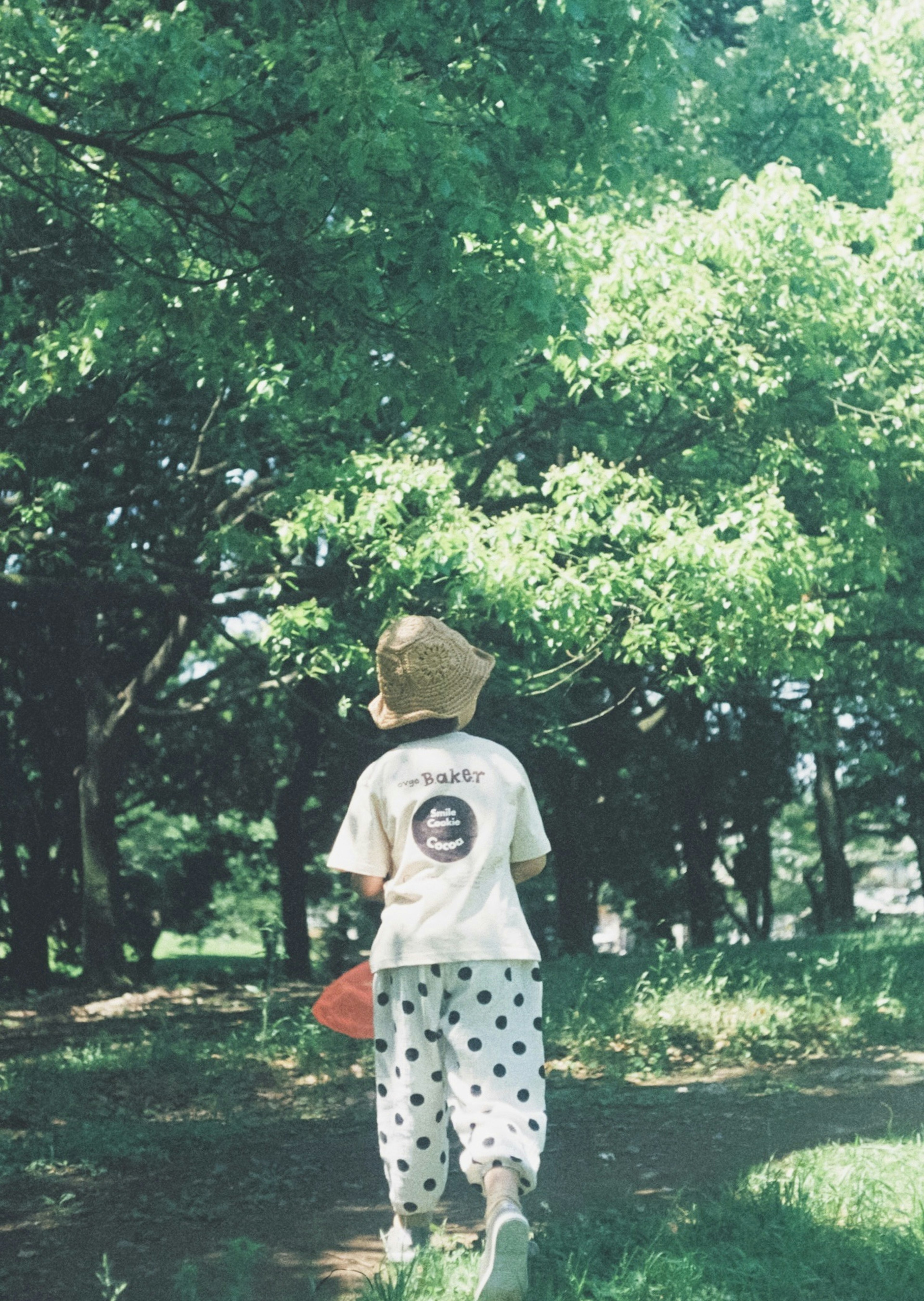 Child walking in a forest wearing a white shirt and polka dot pants