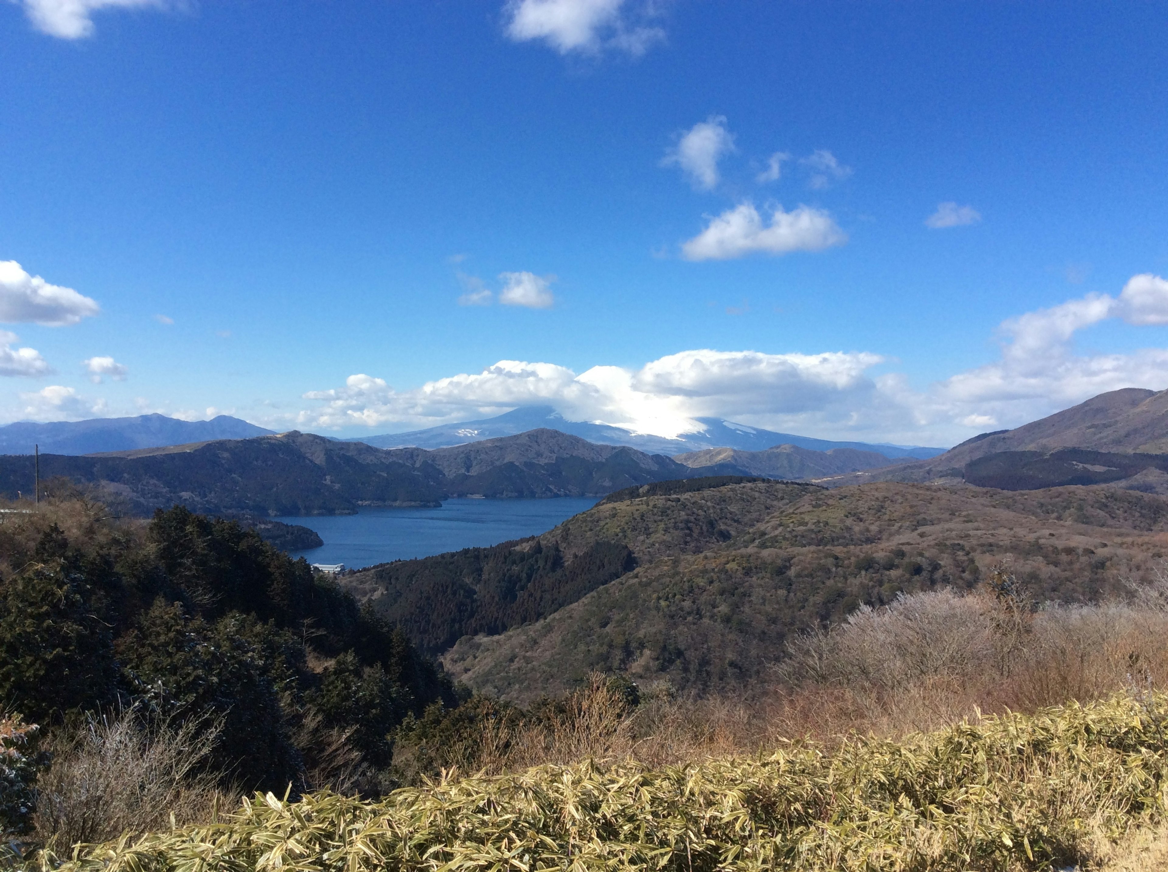 Scenic view of mountains and a lake under a blue sky with white clouds