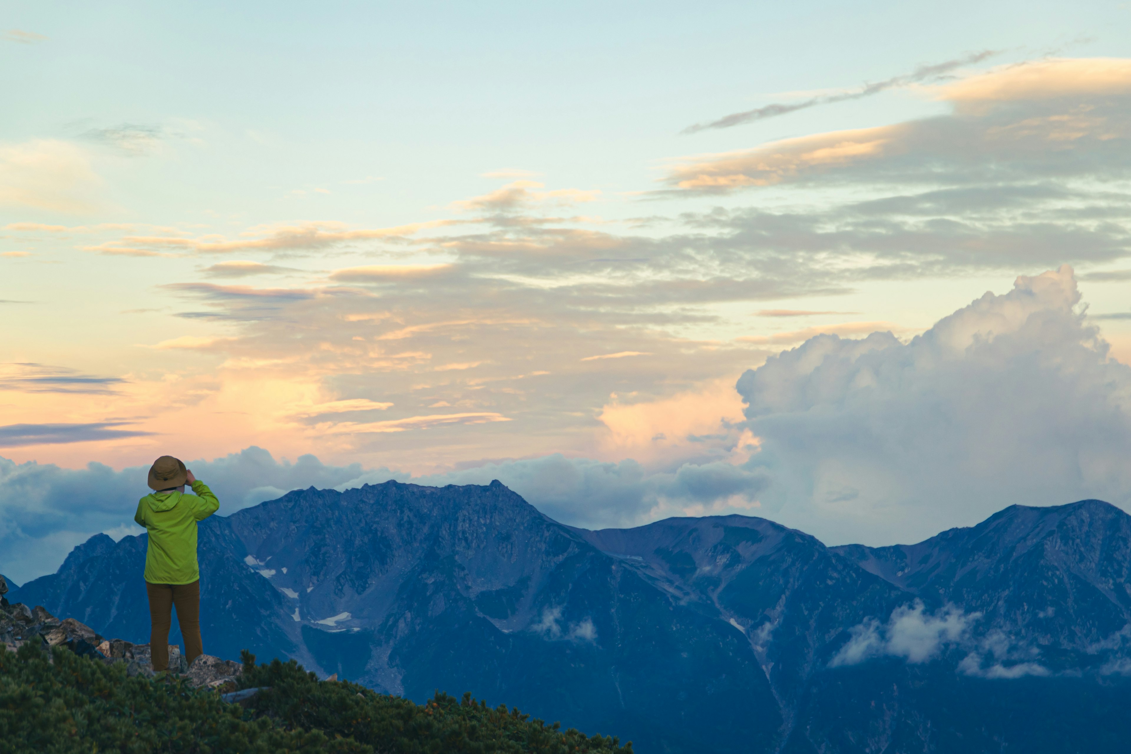 Silueta de una persona mirando al atardecer desde una cima montañosa