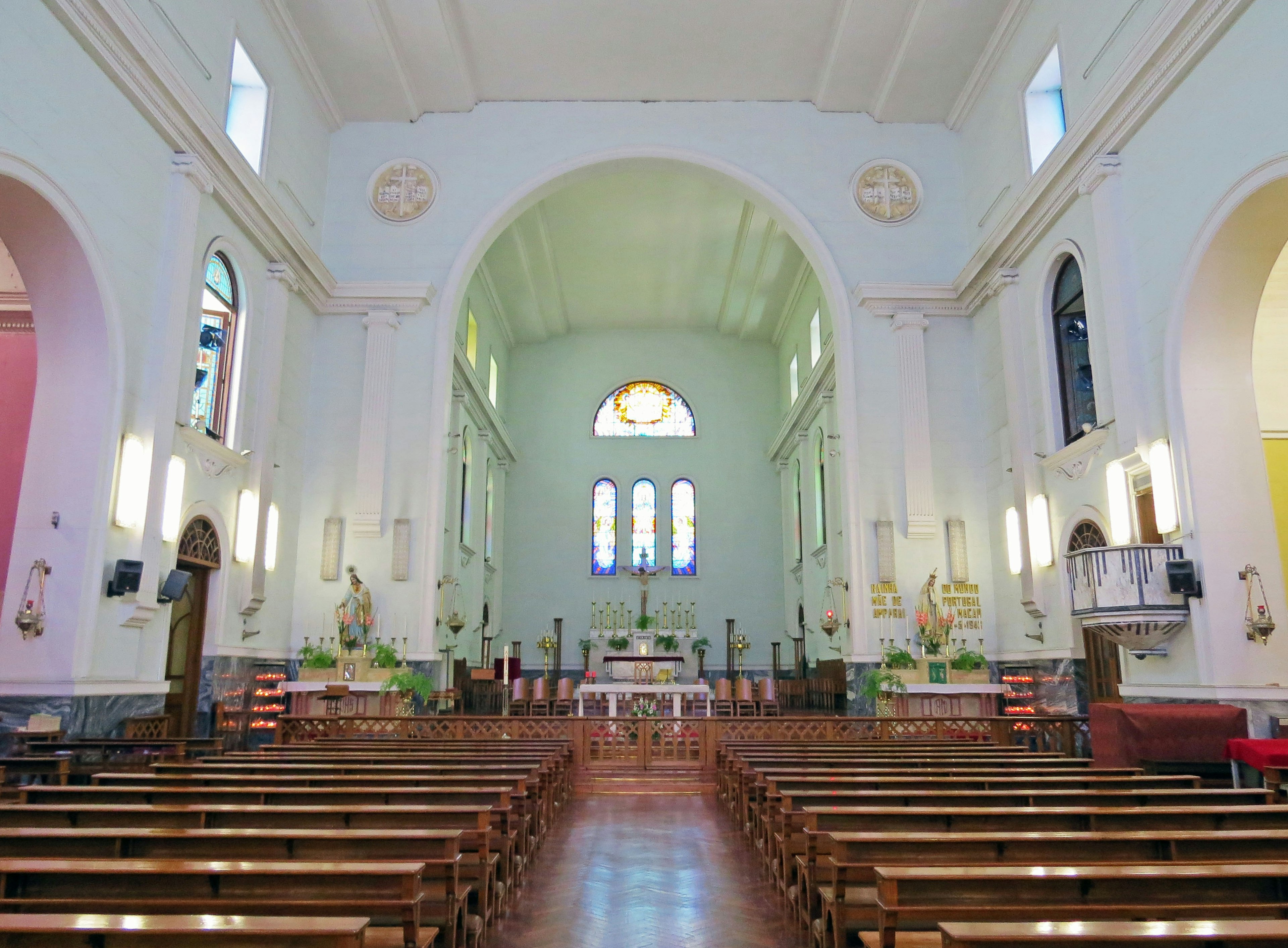 Interior gereja berwarna cerah dengan bangku rapi dan dinding dekoratif