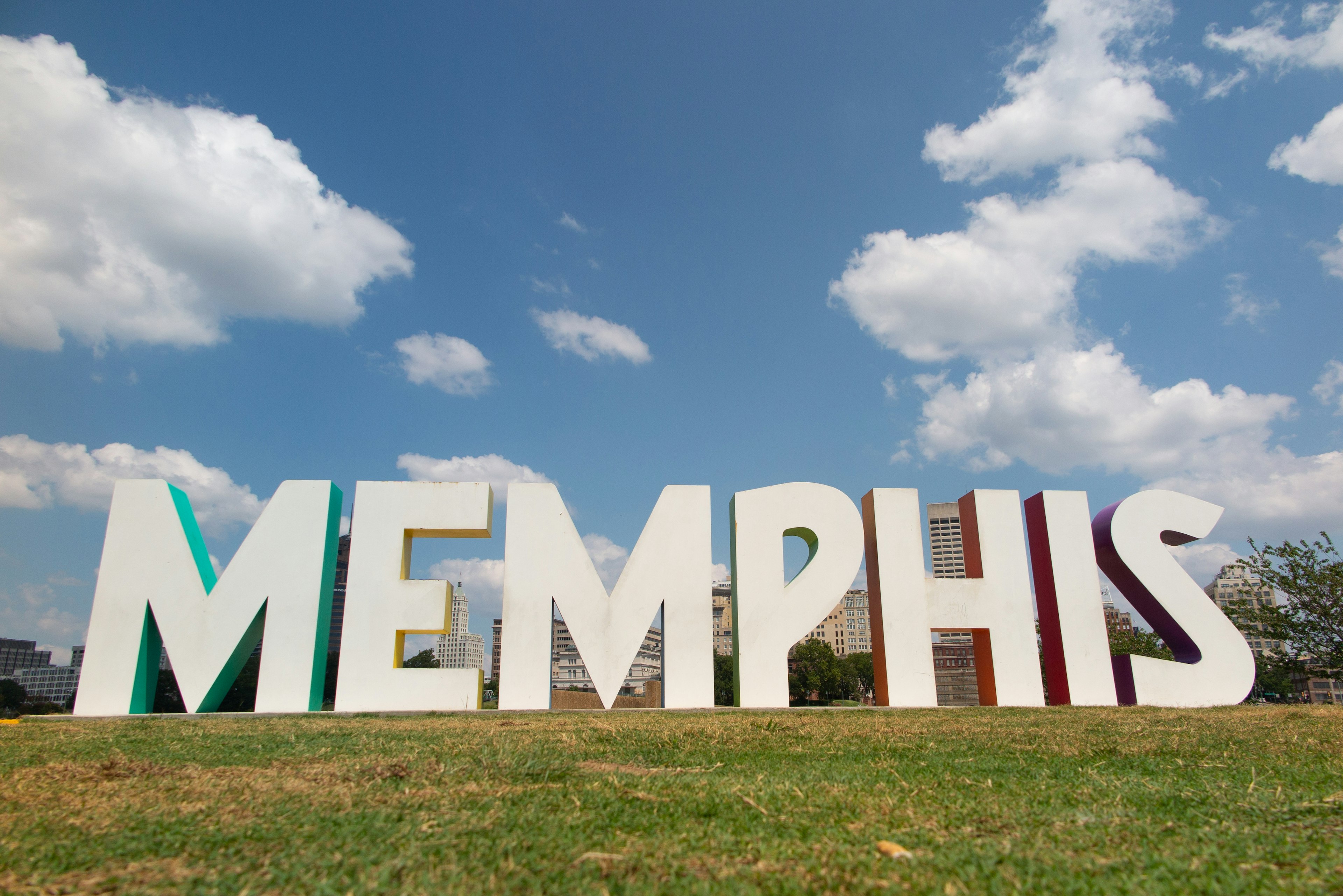 Large sign spelling MEMPHIS on green grass under a blue sky