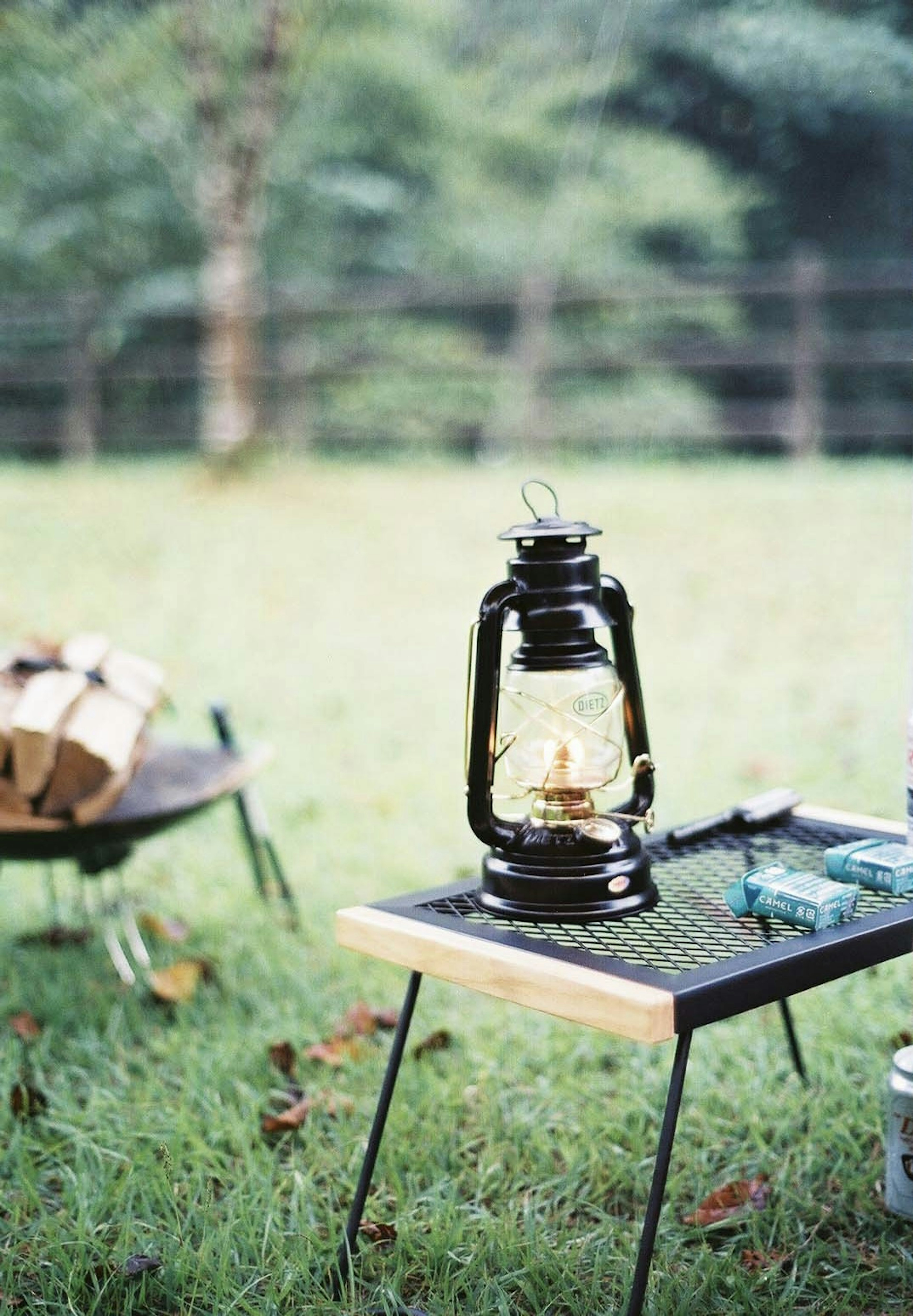 Une lanterne noire sur une table en bois dans une zone herbeuse verte