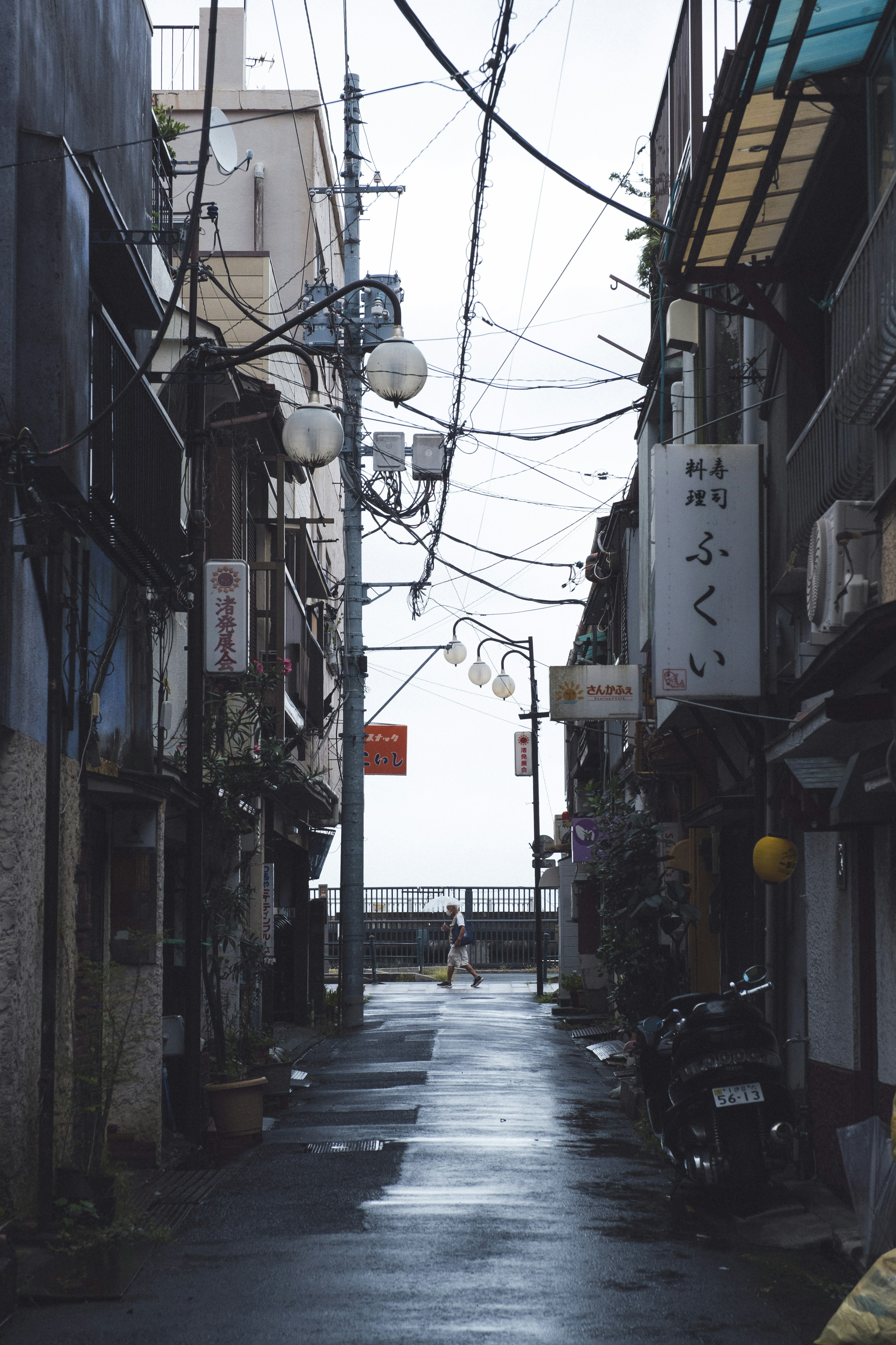 静かな路地に雨が残り古い建物が立ち並ぶ