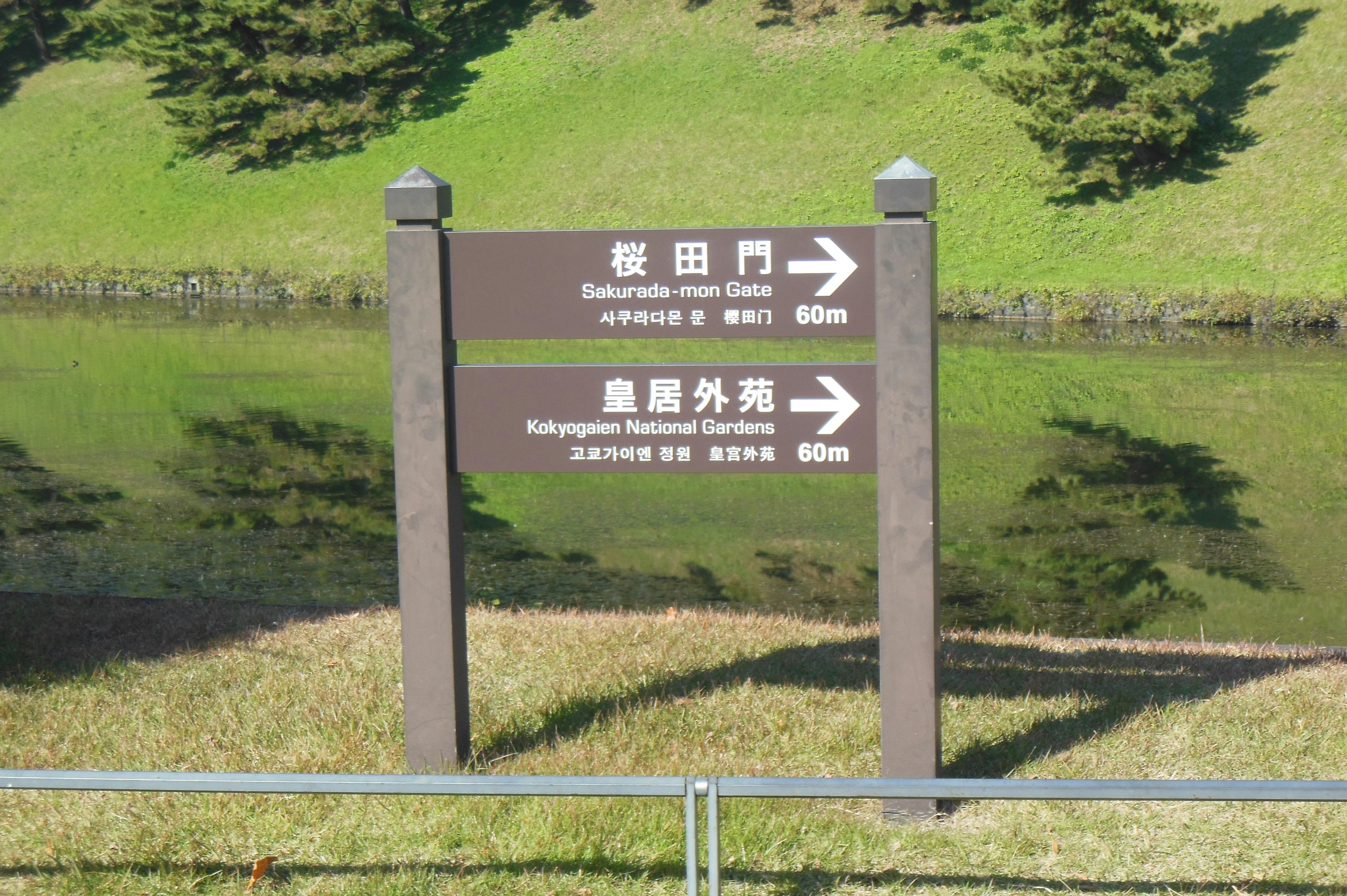 Signpost indicating directions with a green lawn and pond in the background