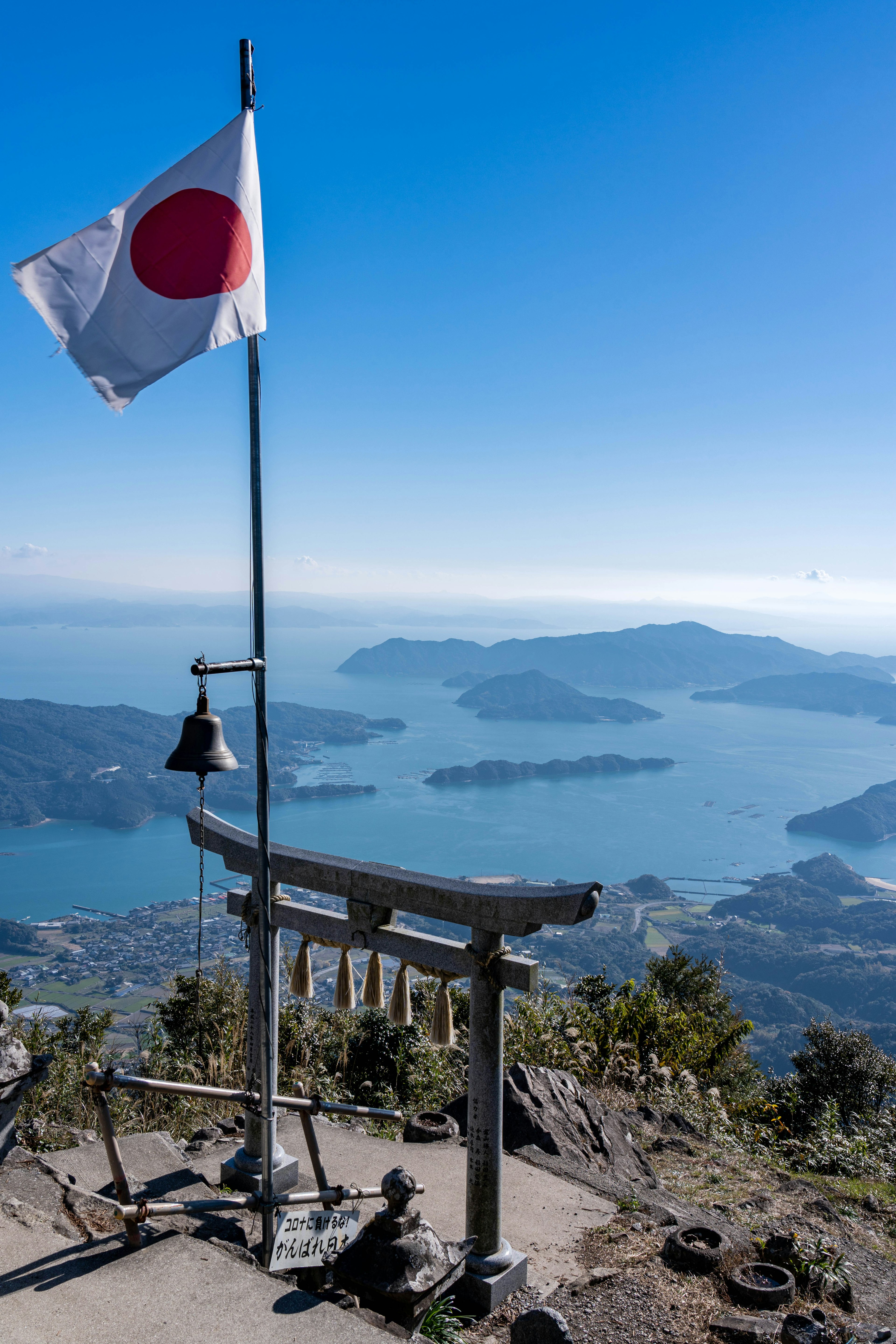 Panoramablick von einem Berggipfel mit einem Torii und der japanischen Flagge