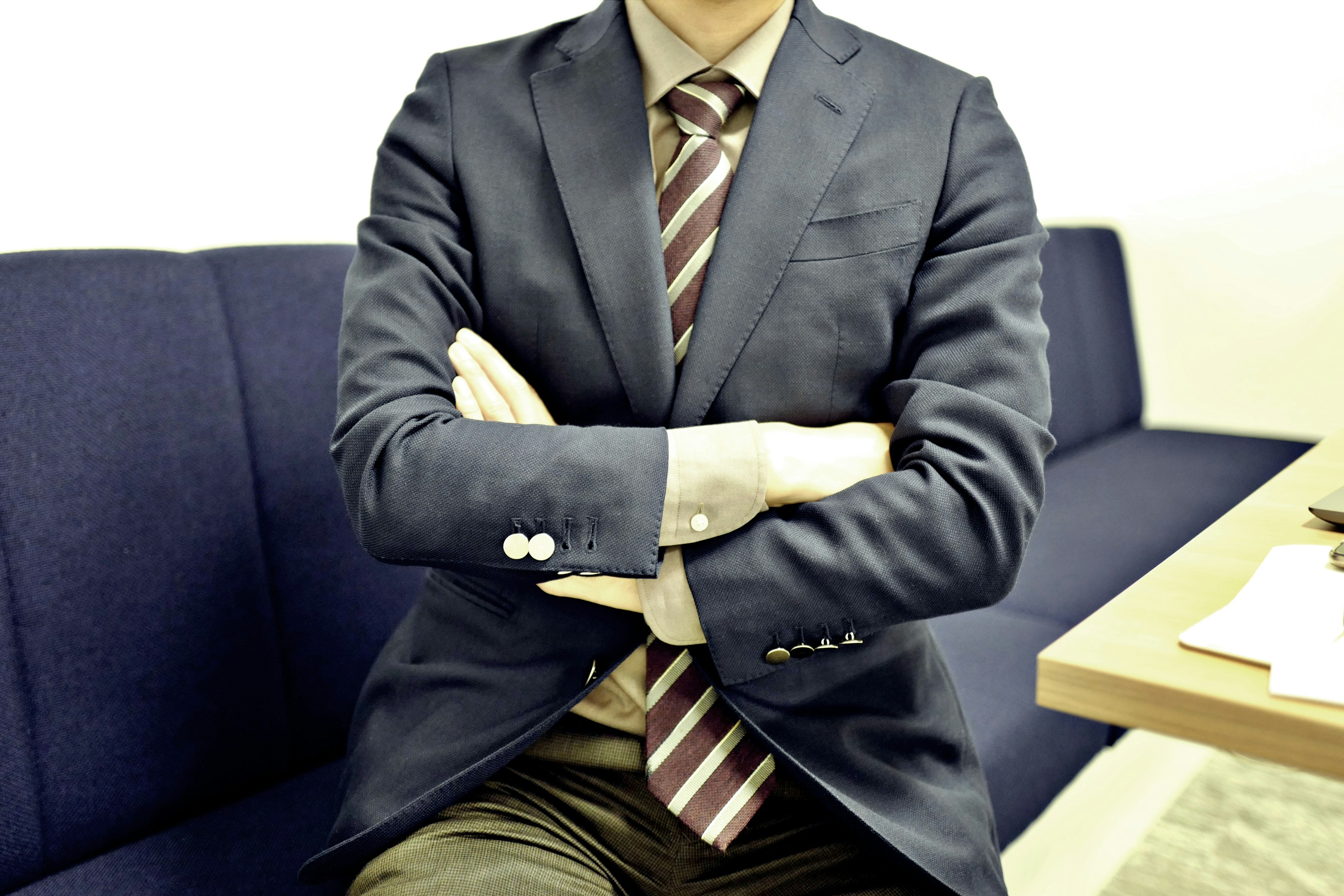 A man in a suit with crossed arms sitting in an office setting