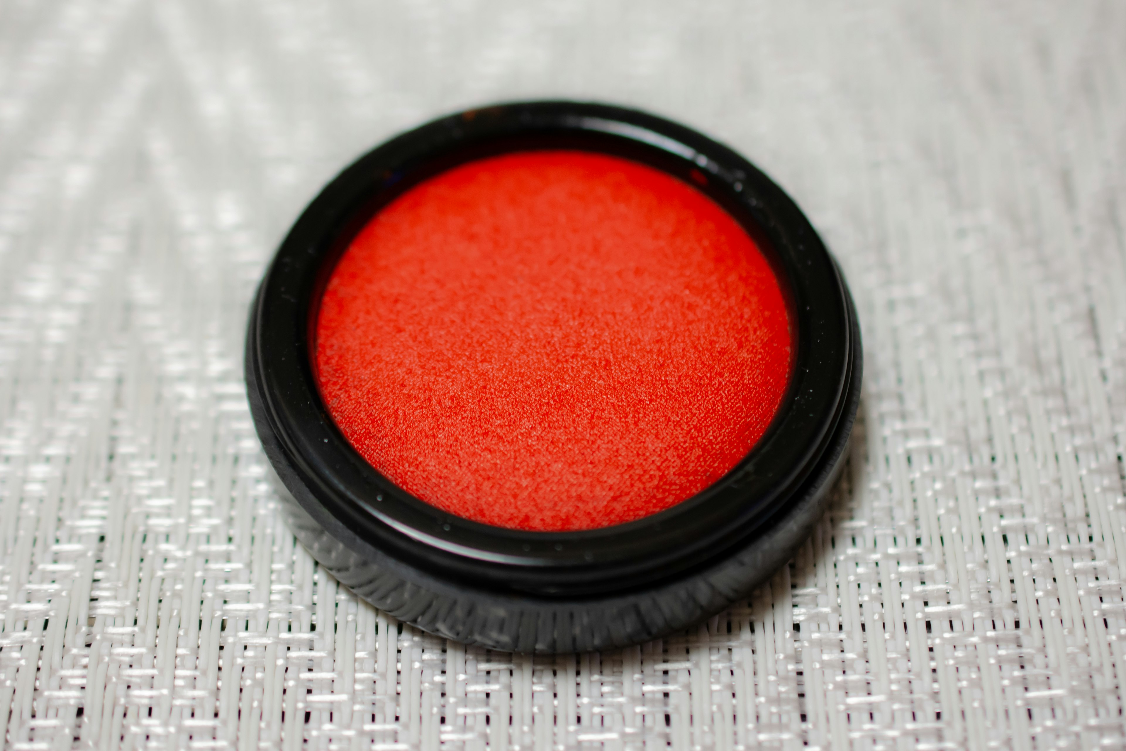 Red powder cosmetic in a black container