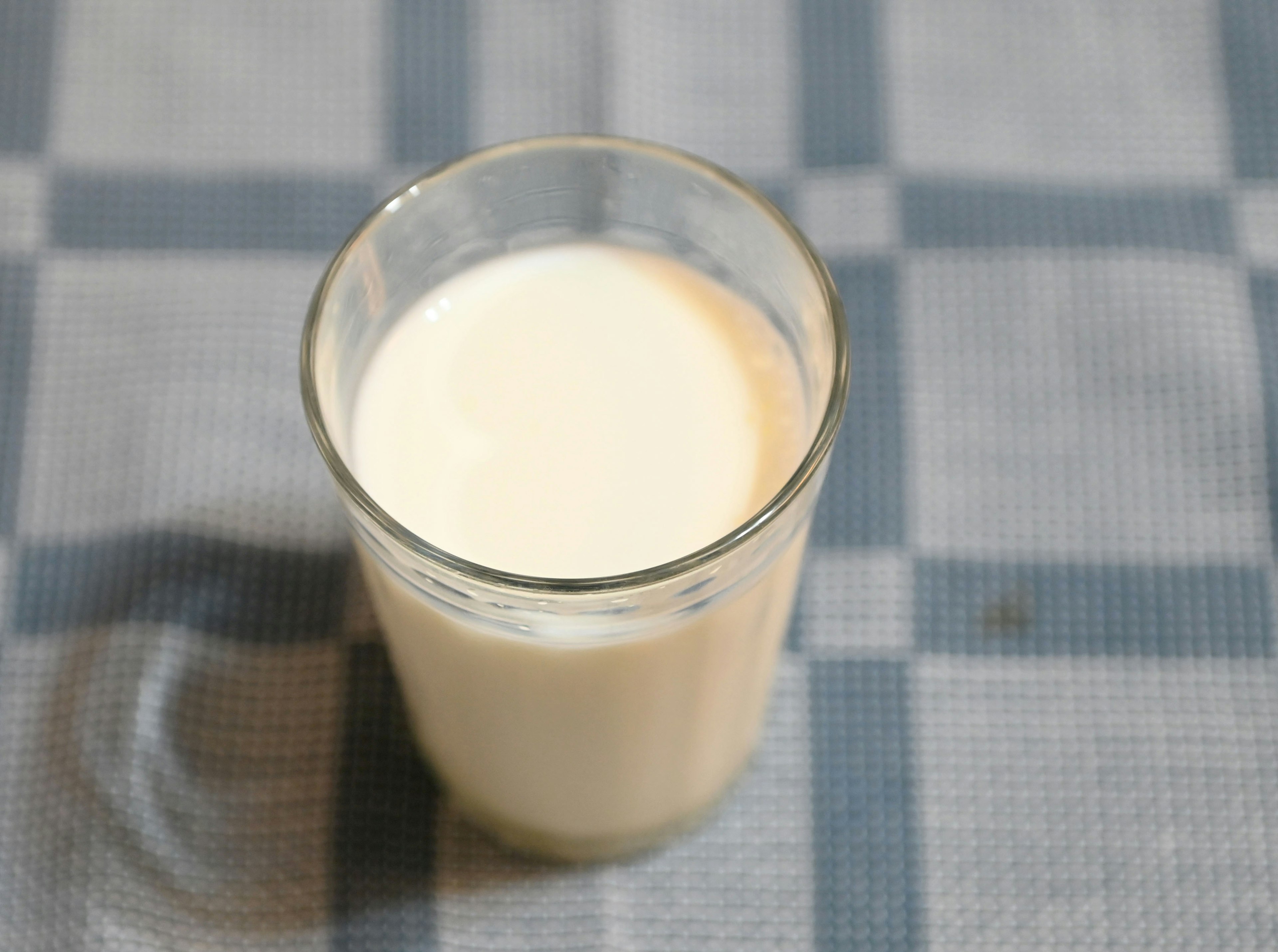 Ein Glas mit weißer Milch auf einem karierten Tischdecken