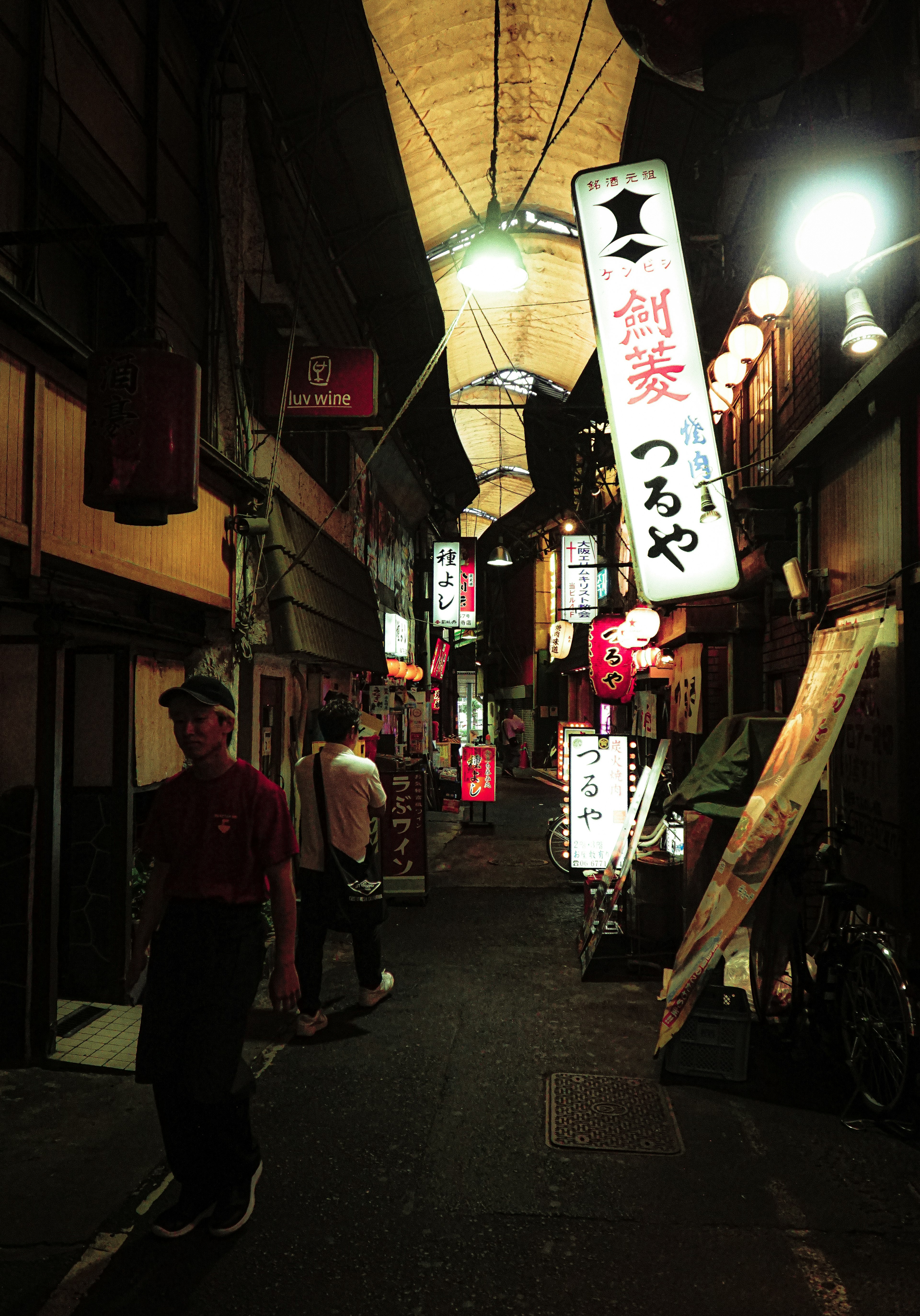 Blick auf eine japanische Straße mit beleuchteten Restaurantschildern in einer engen Gasse