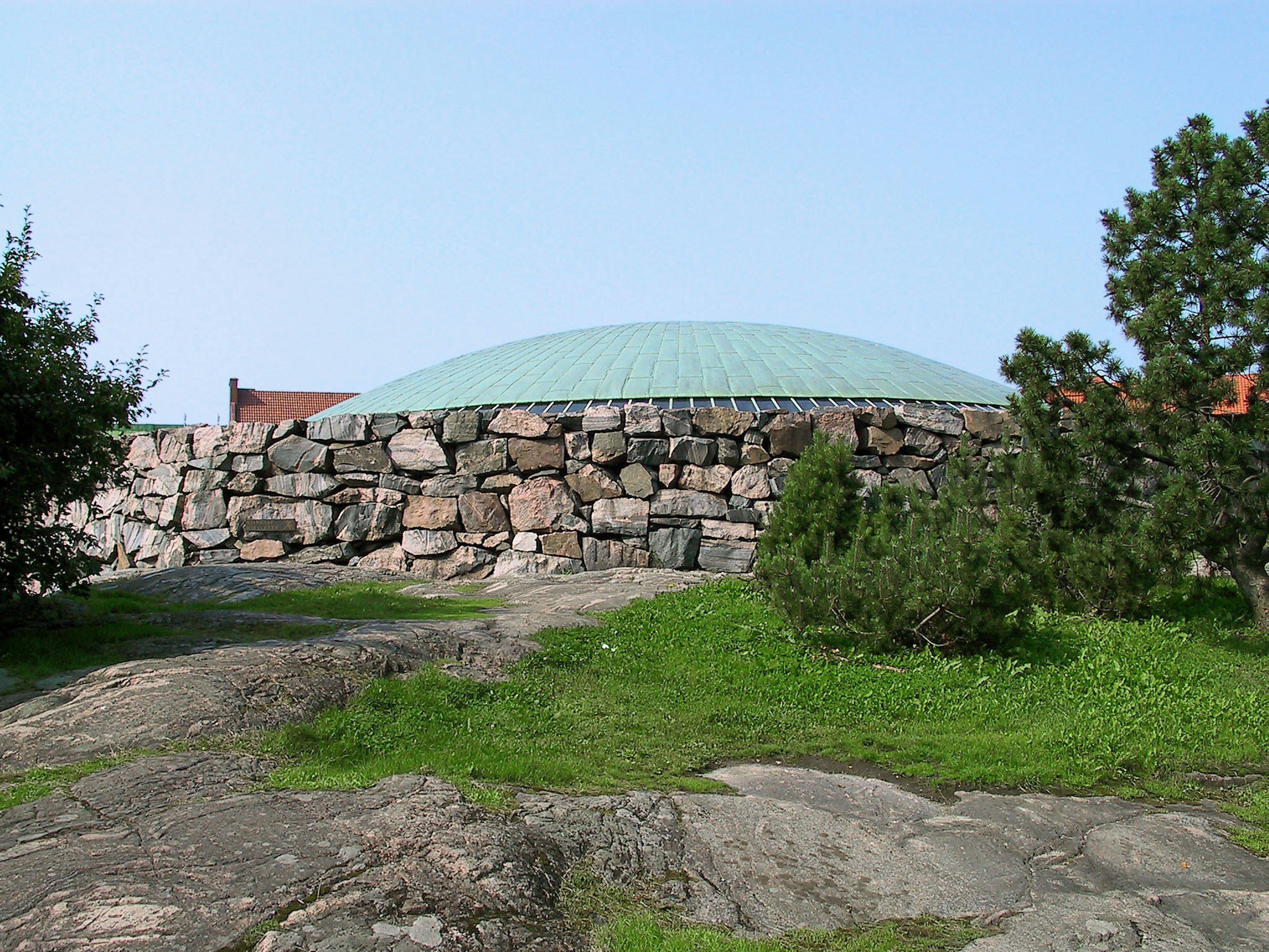 A stone building with a green roof situated on rocky terrain