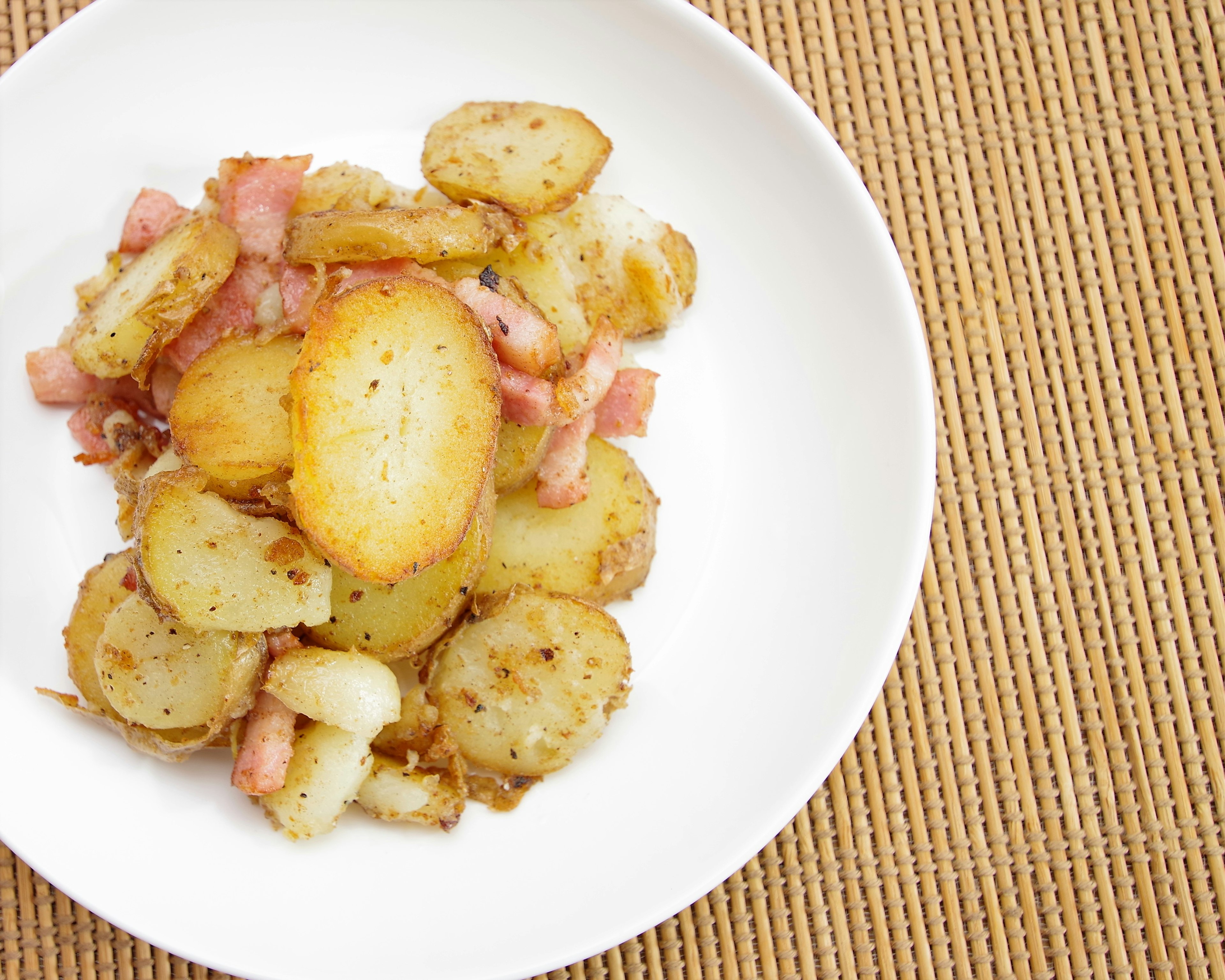 Bacon croccante e patate arrosto serviti in un piatto bianco