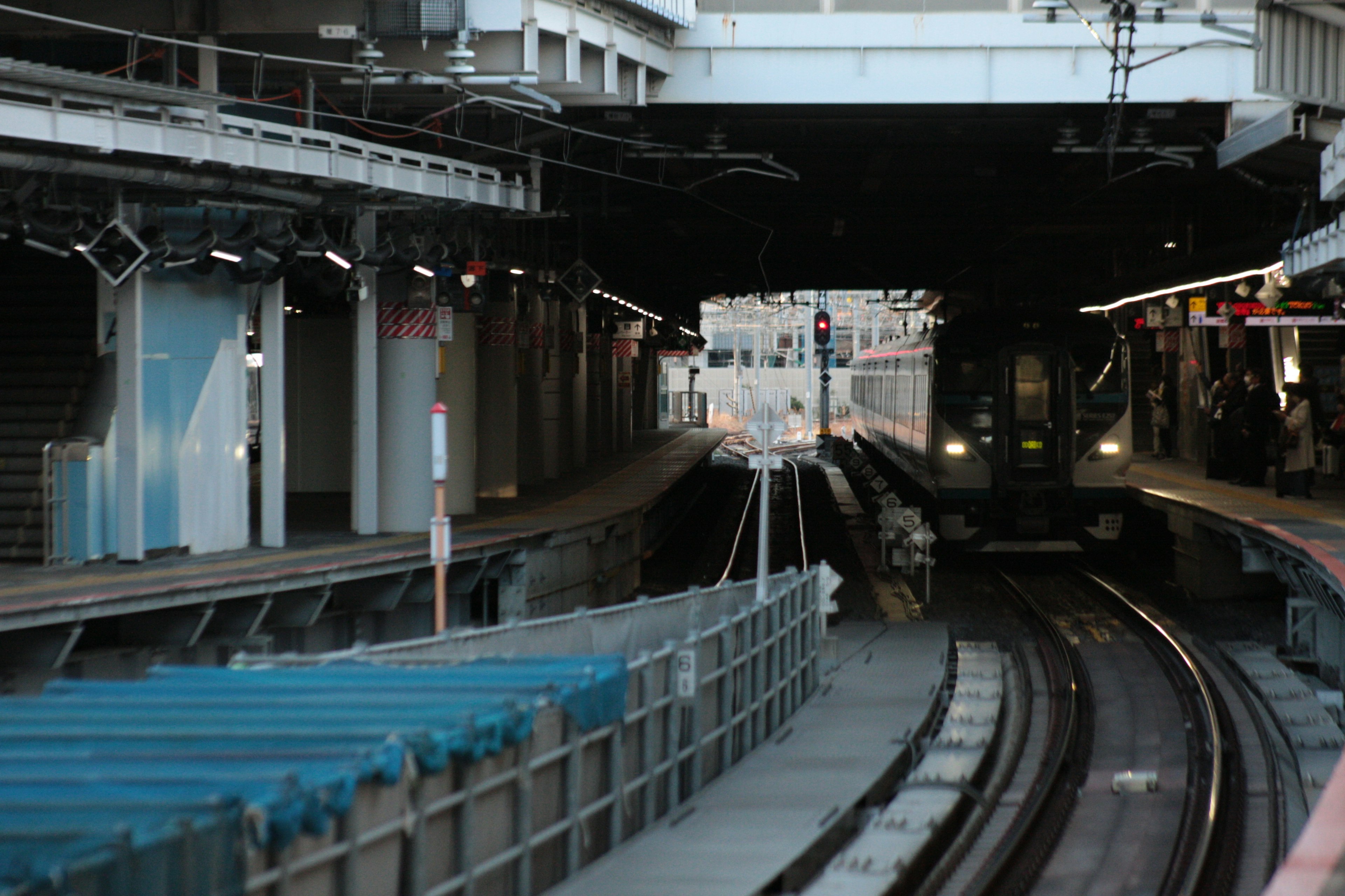 Train approaching on the tracks at a dimly lit station