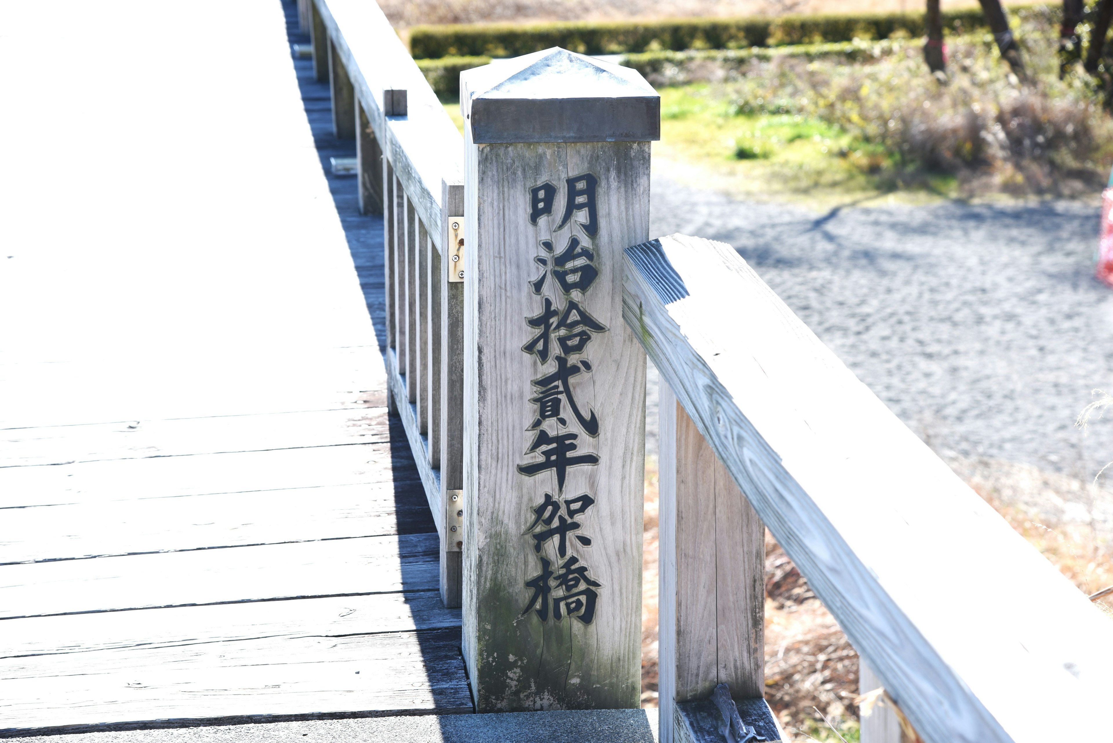 Holzpfeiler mit Inschrift aus der Meiji-Zeit an der Brüstung der Brücke