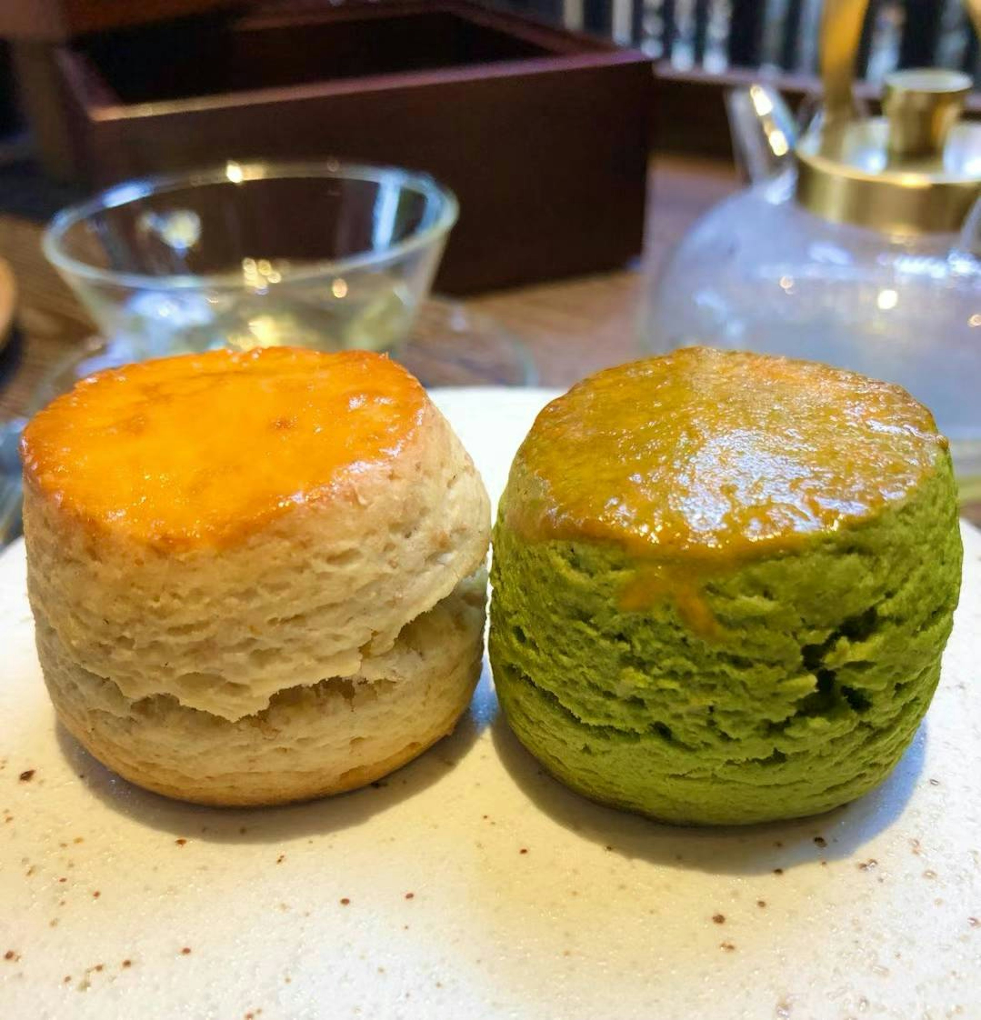 Zwei Scones auf einem Teller Einer mit orangefarbener und der andere mit grüner Garnitur