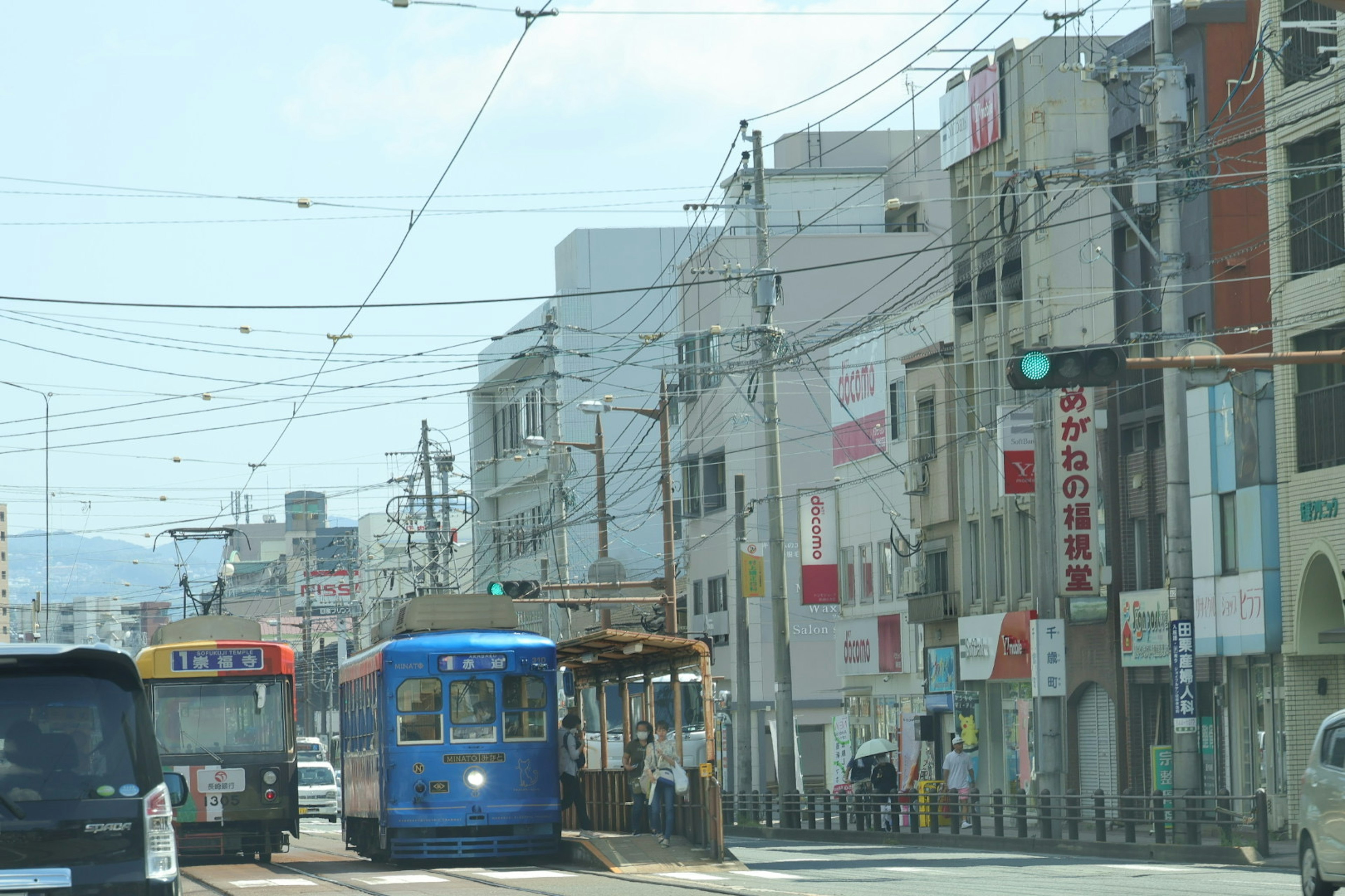 Blue tram traveling through a city street with commercial buildings