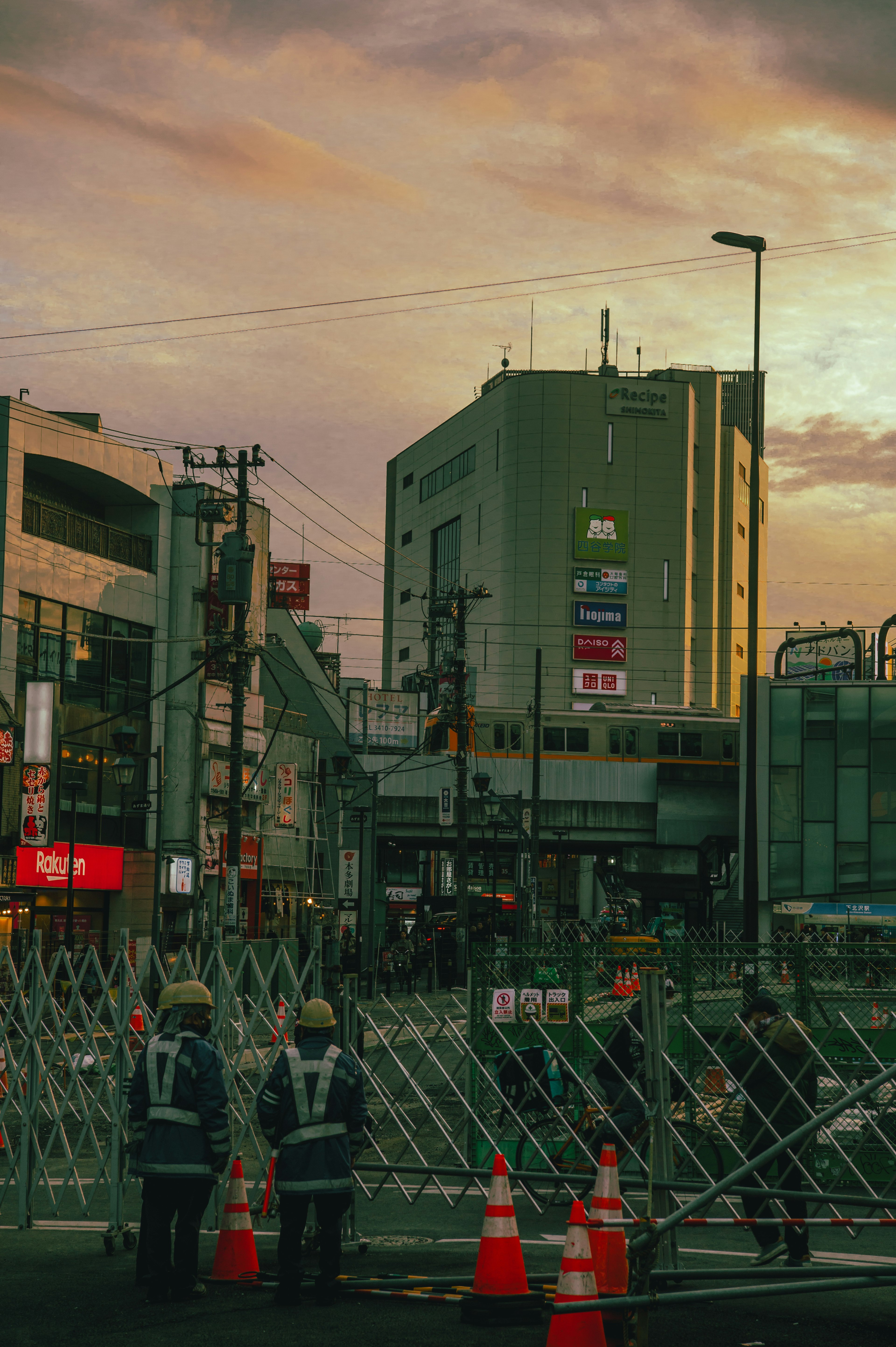 夕焼けの中で交通規制を行う警備員とフェンスのある都市の風景