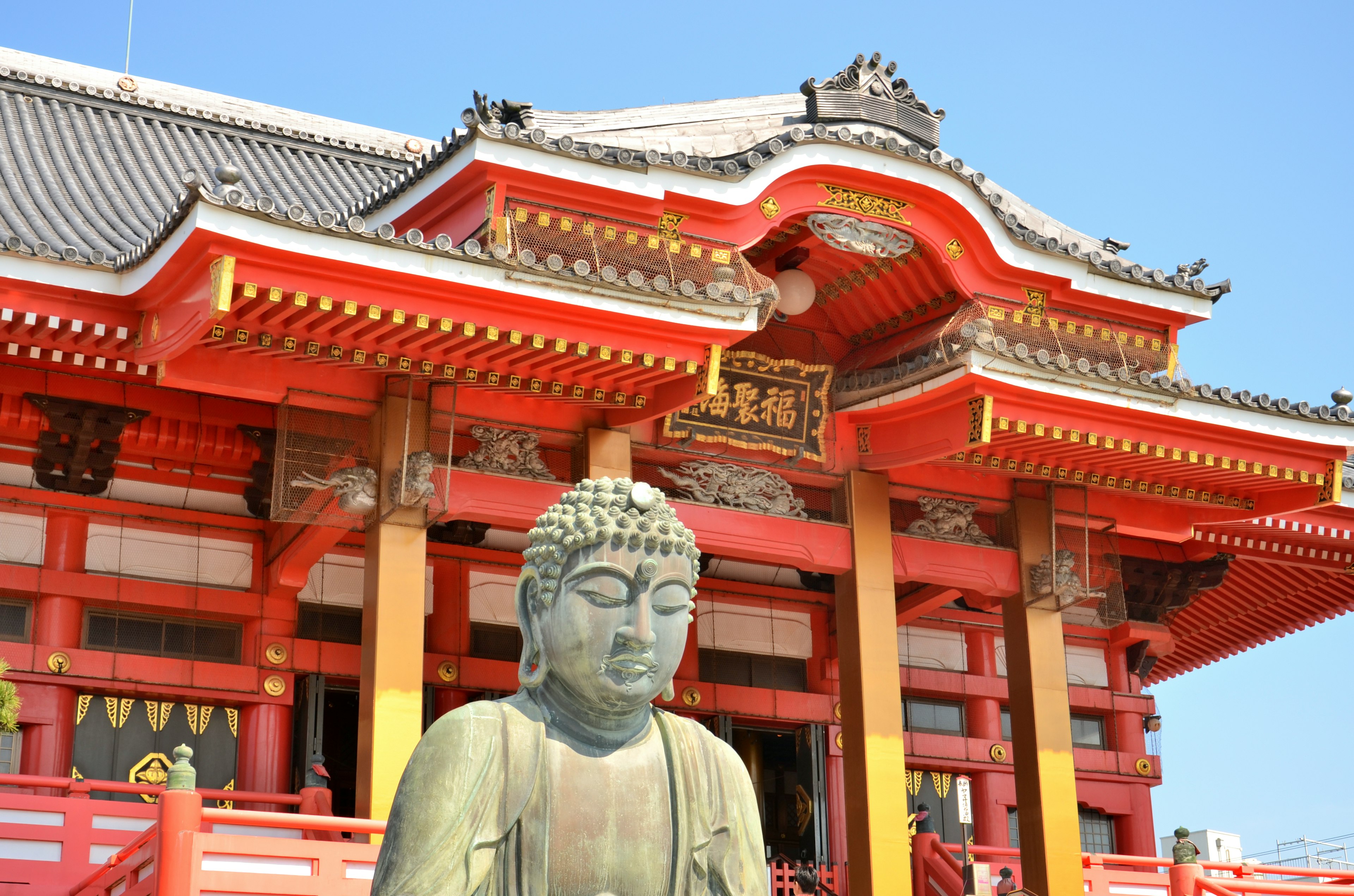 Grande statue de Bouddha devant un temple rouge