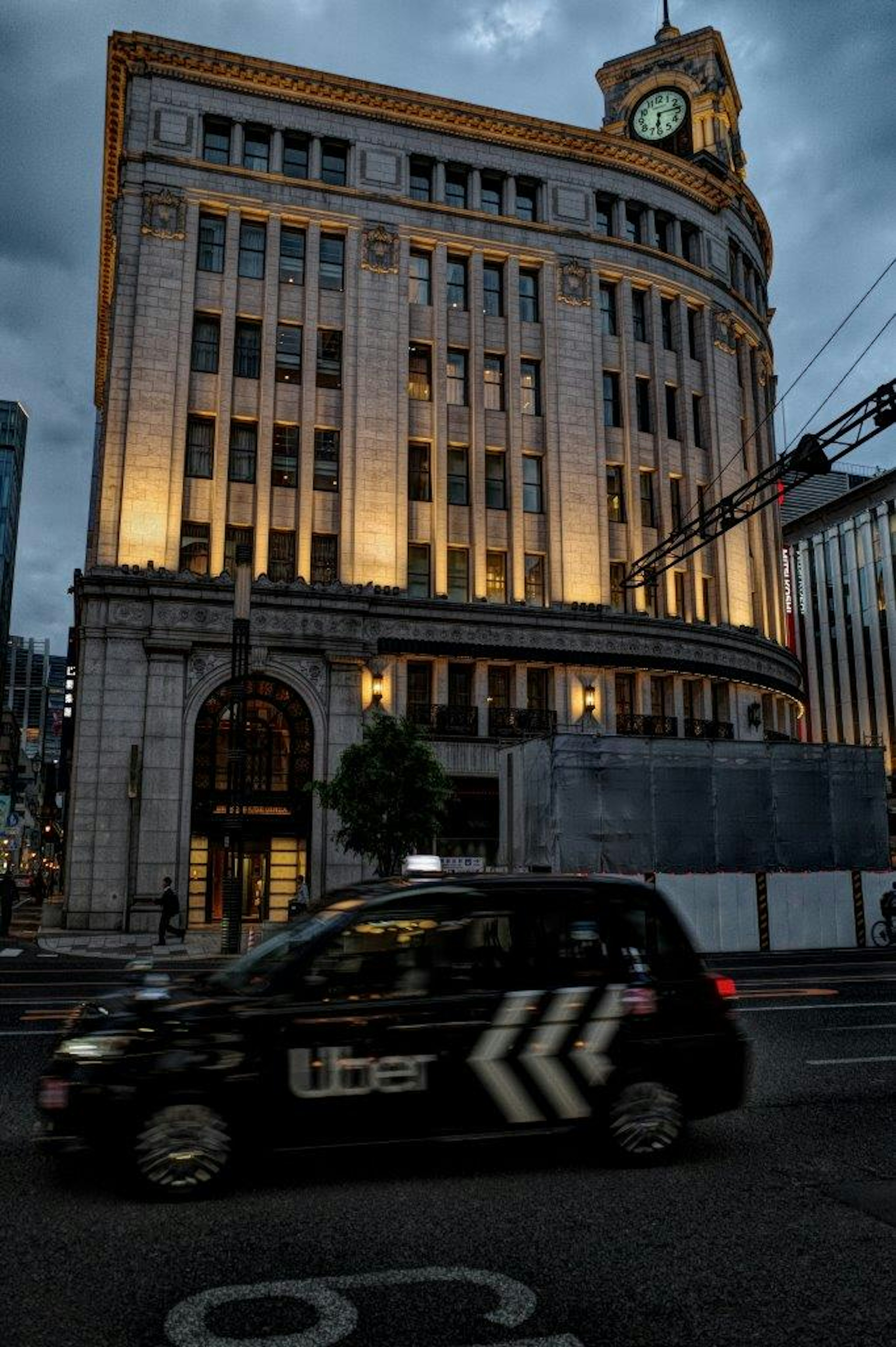 Illuminated historic building at night with an Uber car passing by