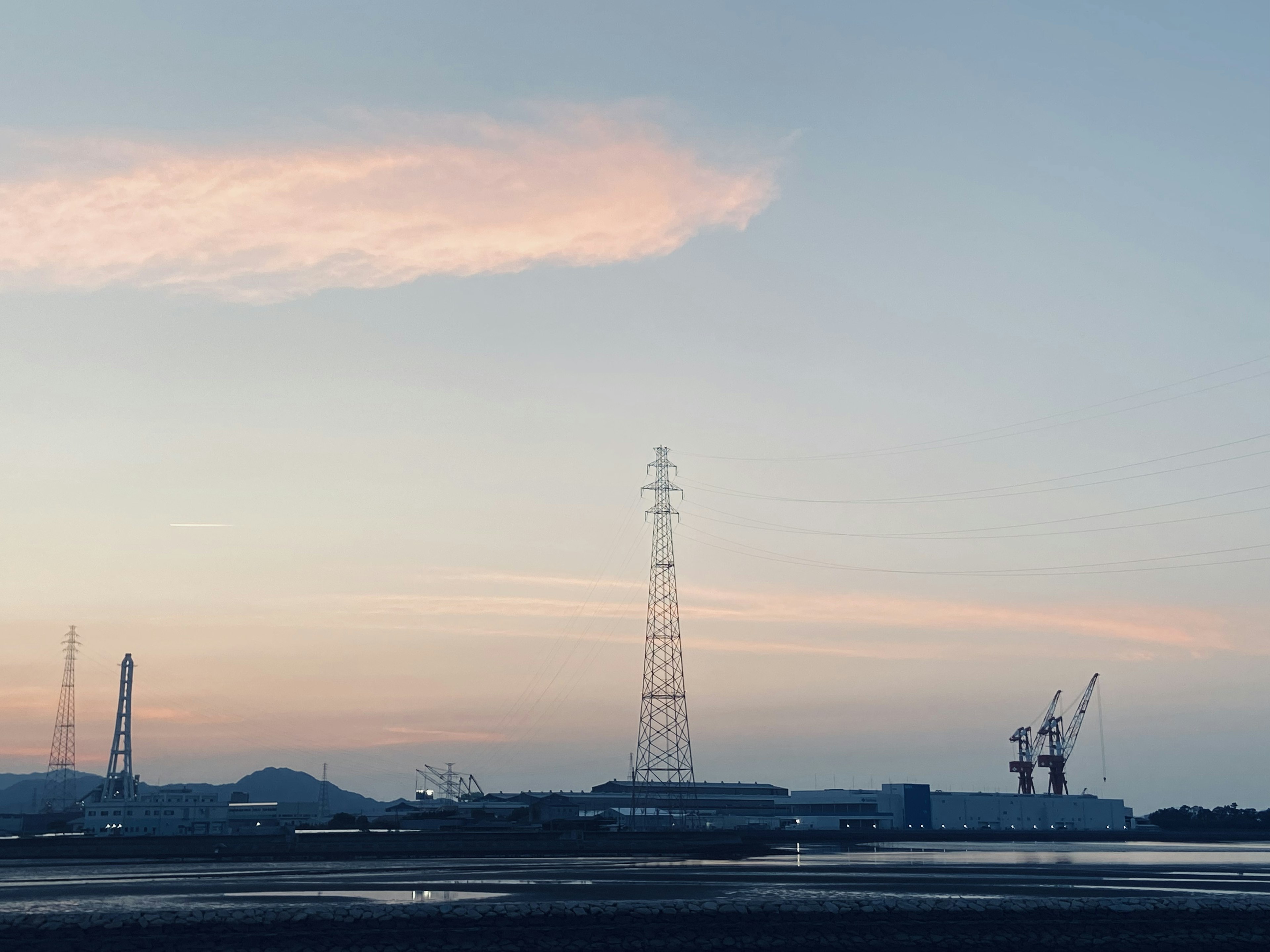 Area industriale con gru contro un cielo al tramonto