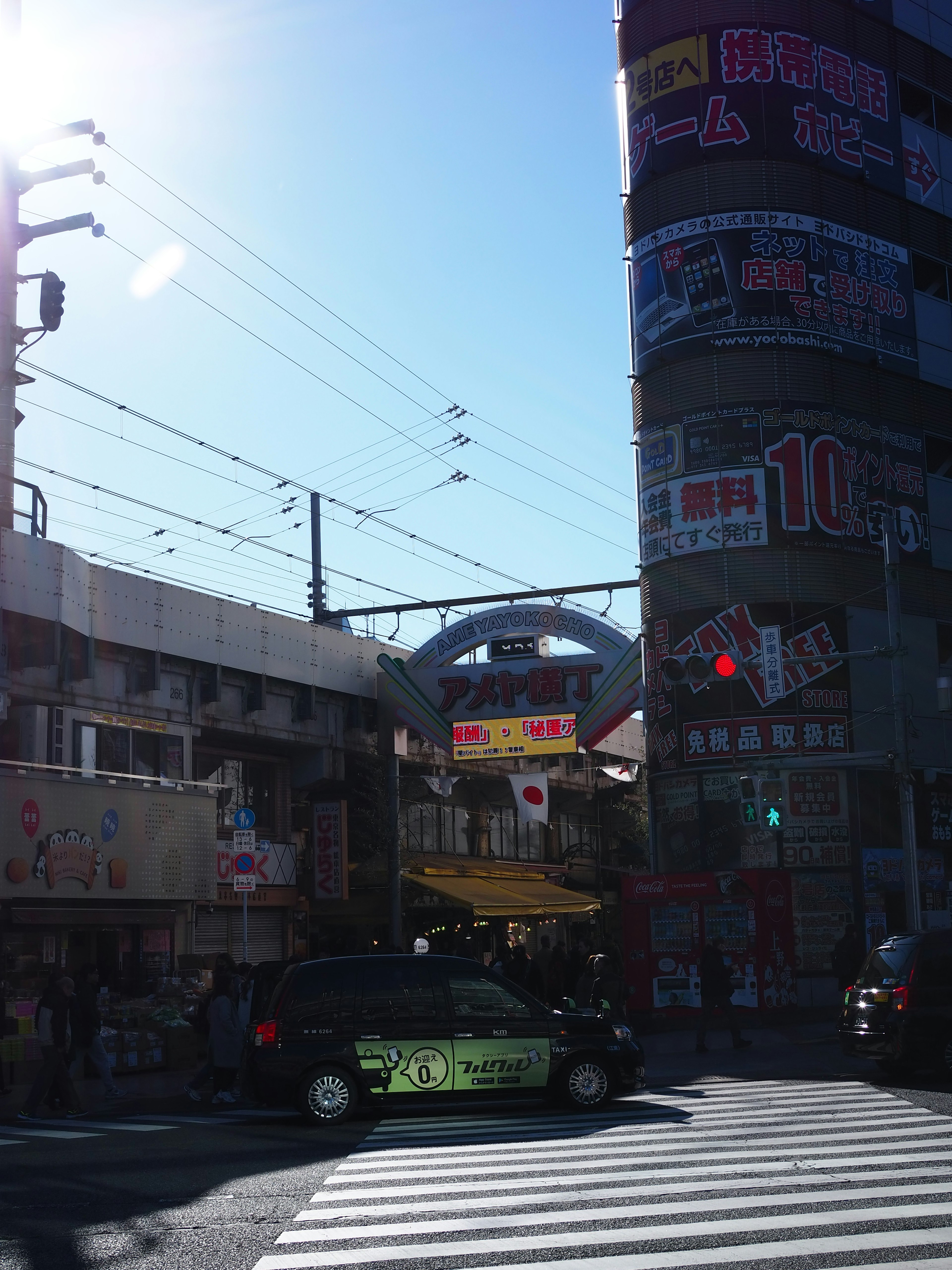 青空の下に広がる繁華街の風景 車が通る交差点と看板が並ぶ商業ビル