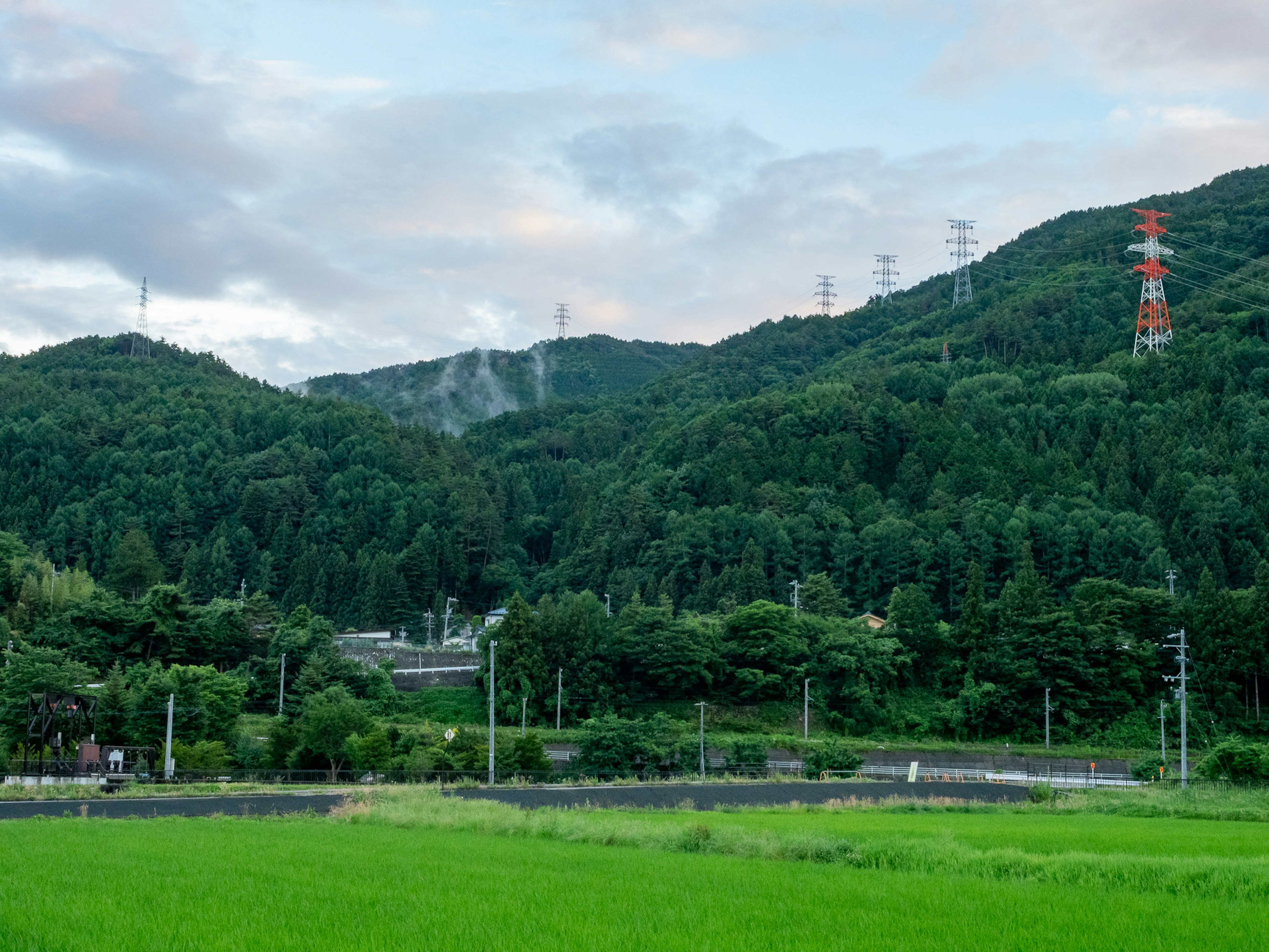 Üppige grüne Berge unter einem blauen Himmel mit weitläufigen Reisfeldern