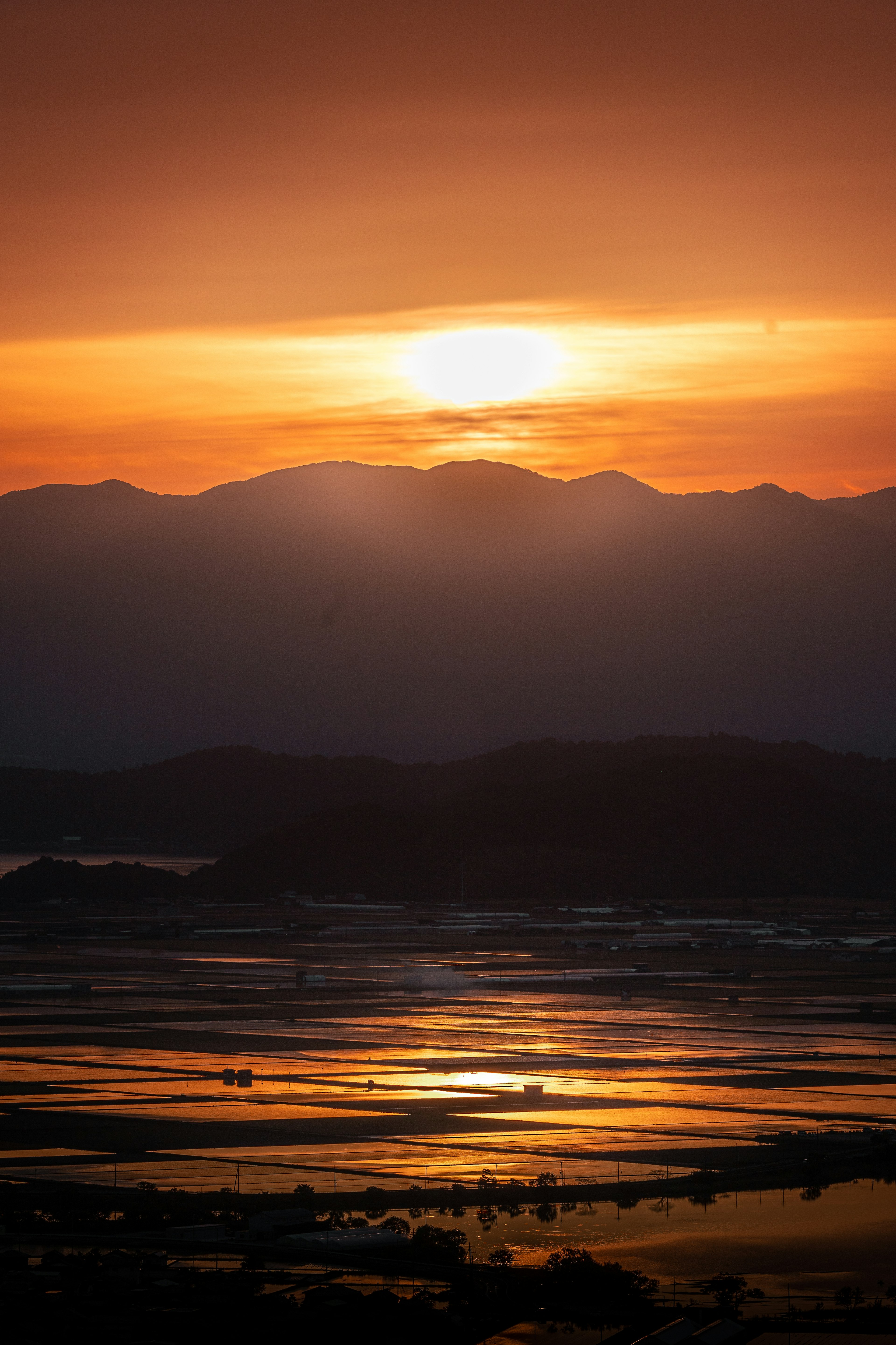 美丽的风景，夕阳在山间落下，橙色光线在水面上反射