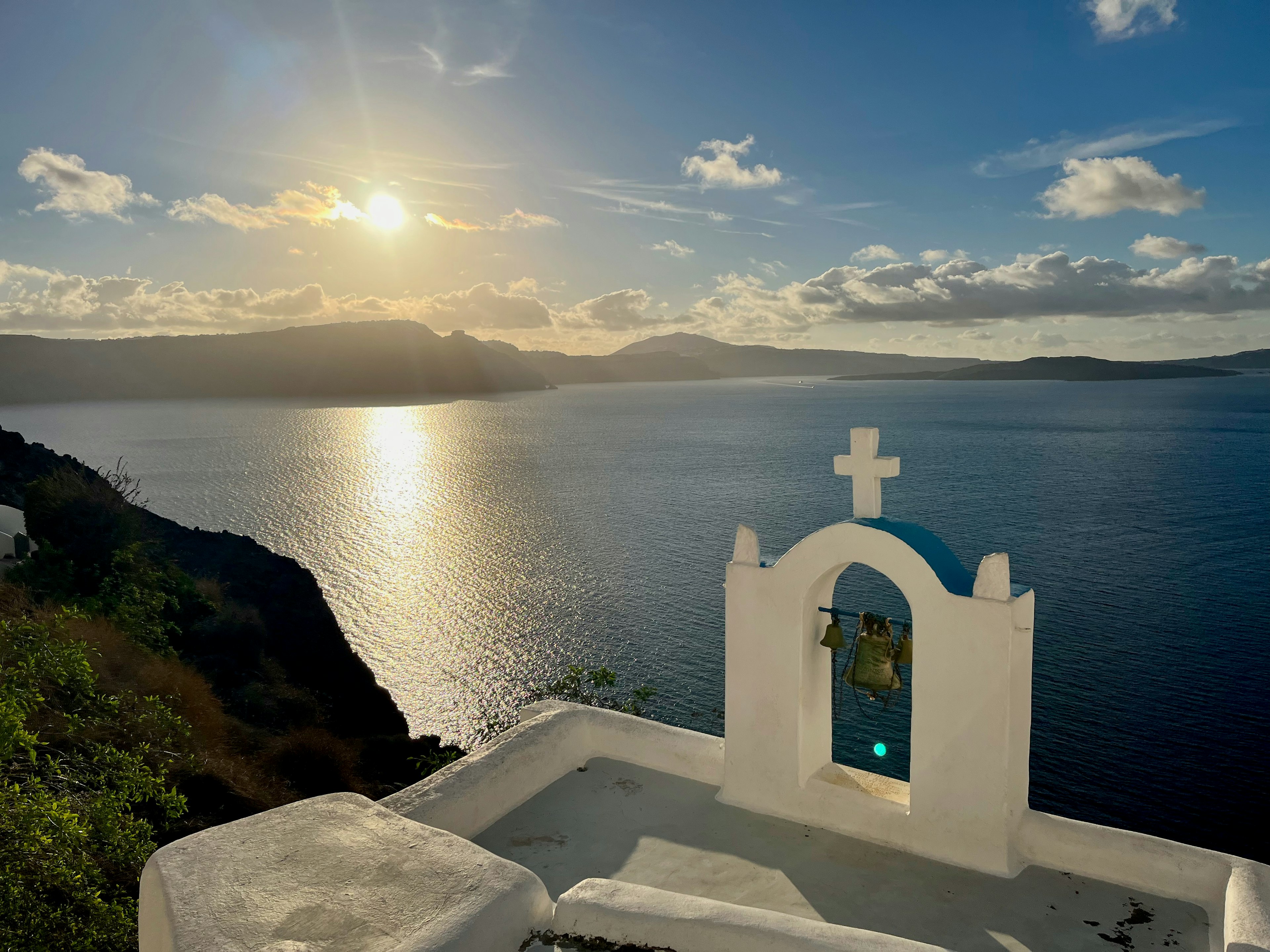 Schöne Aussicht auf das Meer und die strahlende Sonne in Santorin mit einer auffälligen weißen Kirche