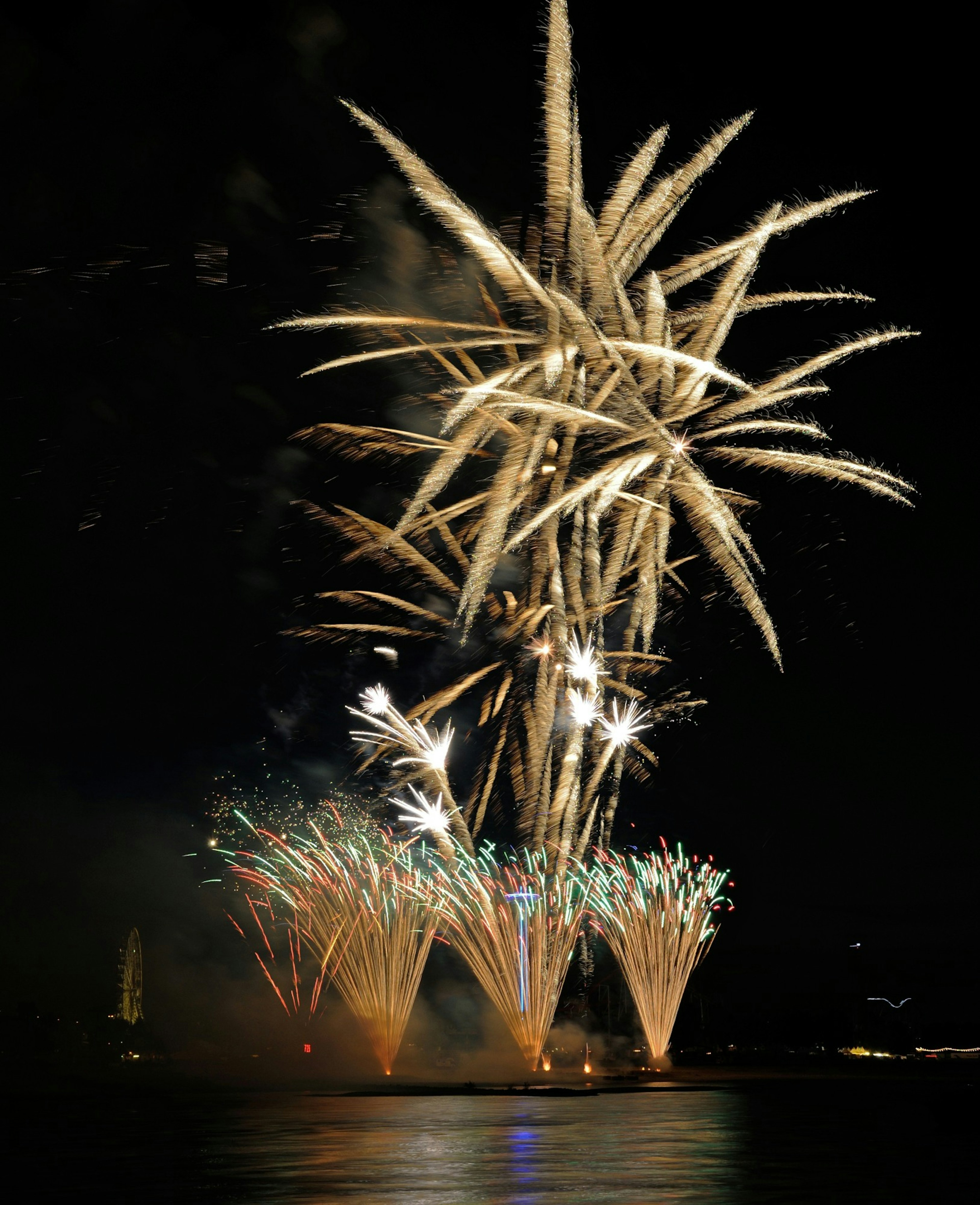 Espectáculo vibrante de fuegos artificiales iluminando el cielo nocturno chispas coloridas reflejándose en el agua