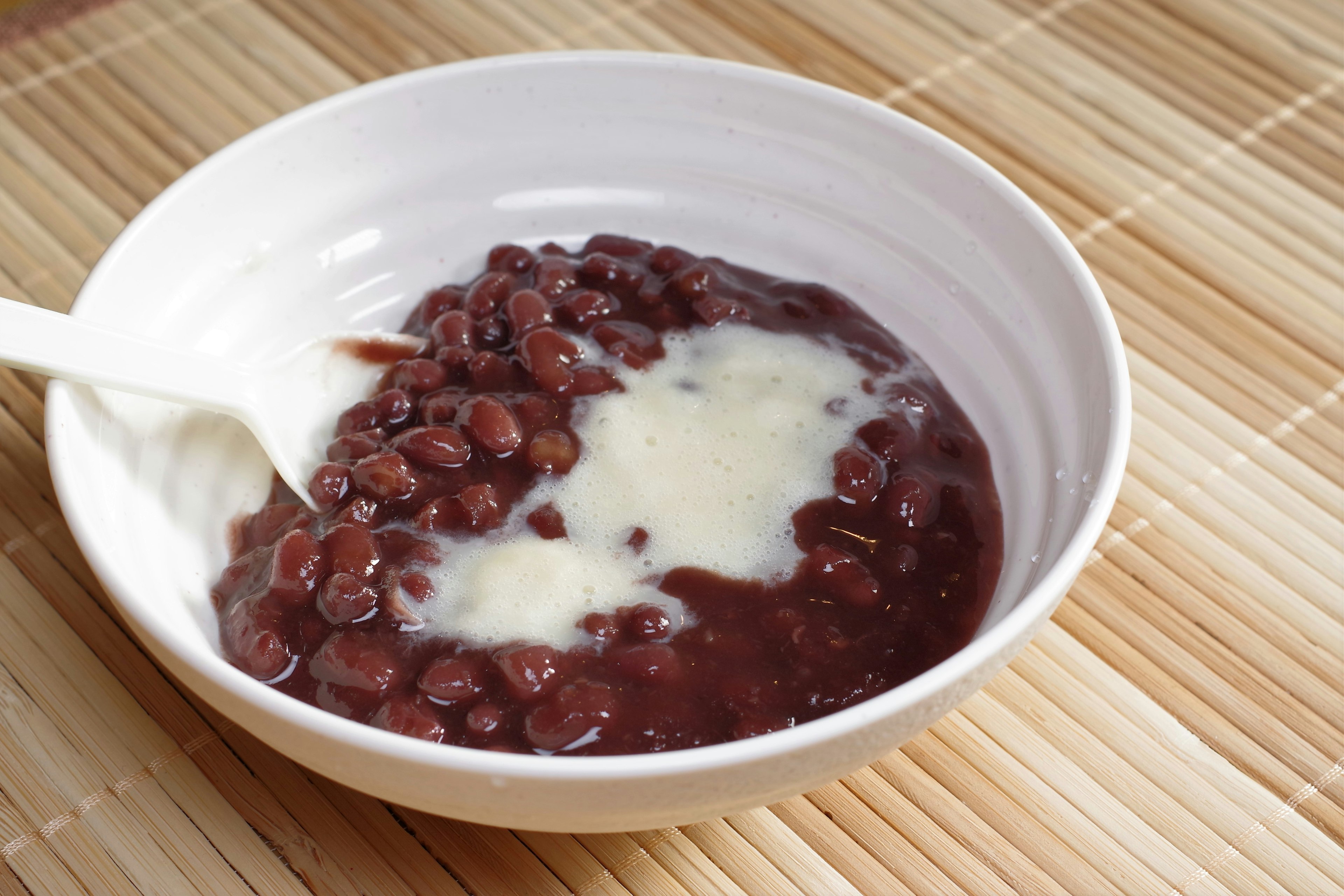 Puding kacang merah dalam mangkuk putih dengan krim di atasnya