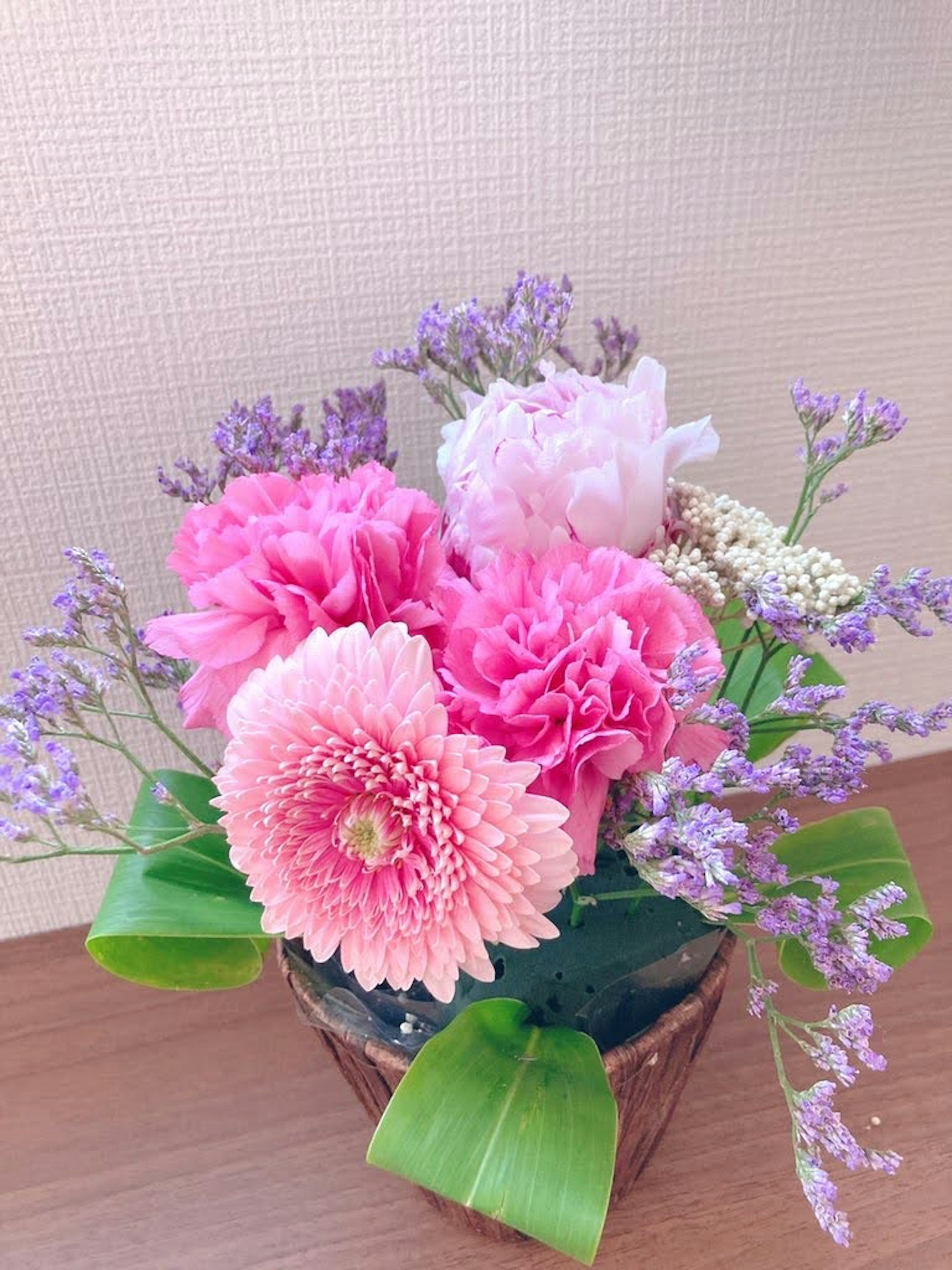 Floral arrangement featuring pink flowers and purple accents in a decorative pot