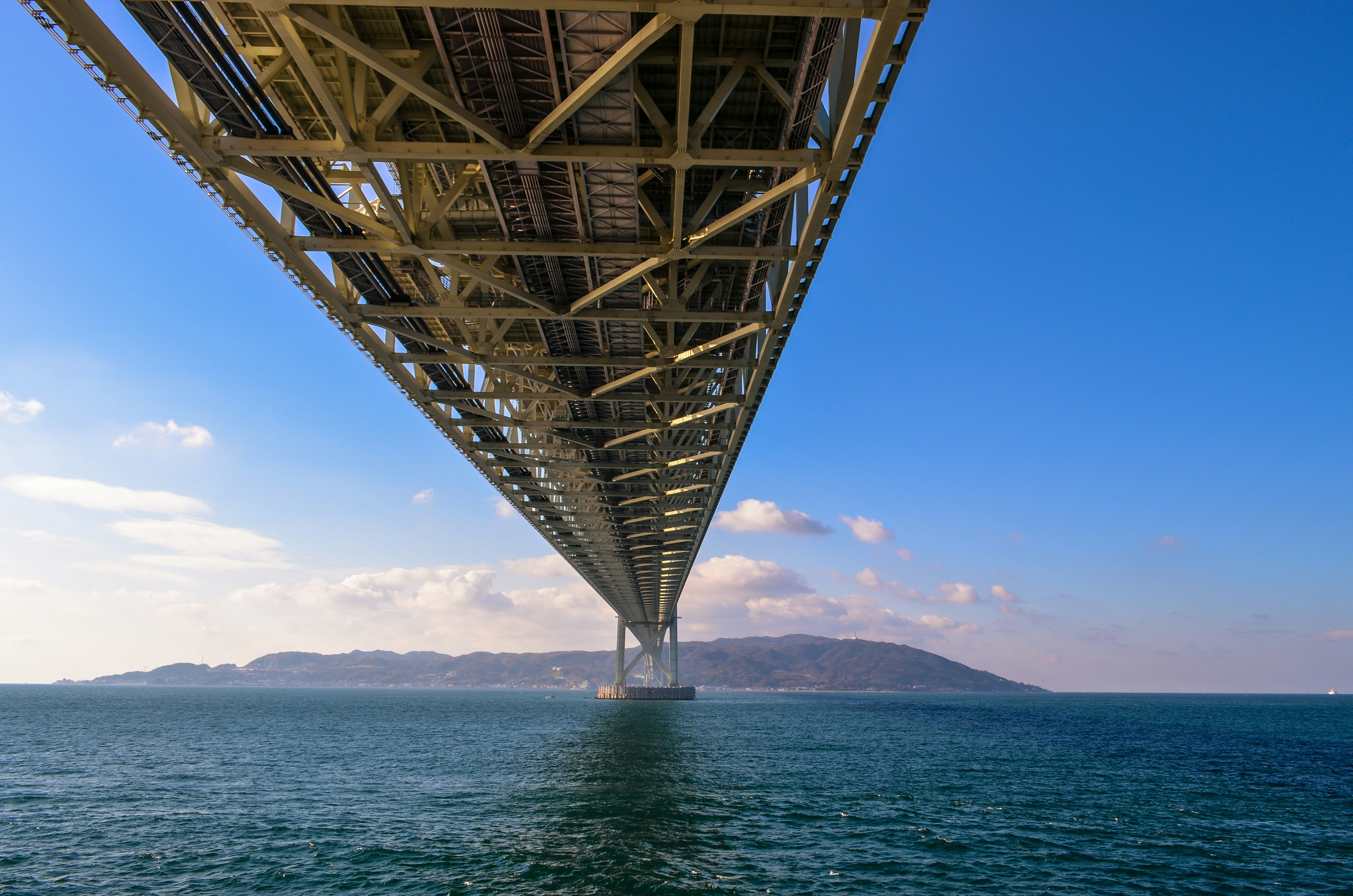 Blick auf eine schöne Meereslandschaft von unter einer Brücke mit blauem Himmel und Wolken