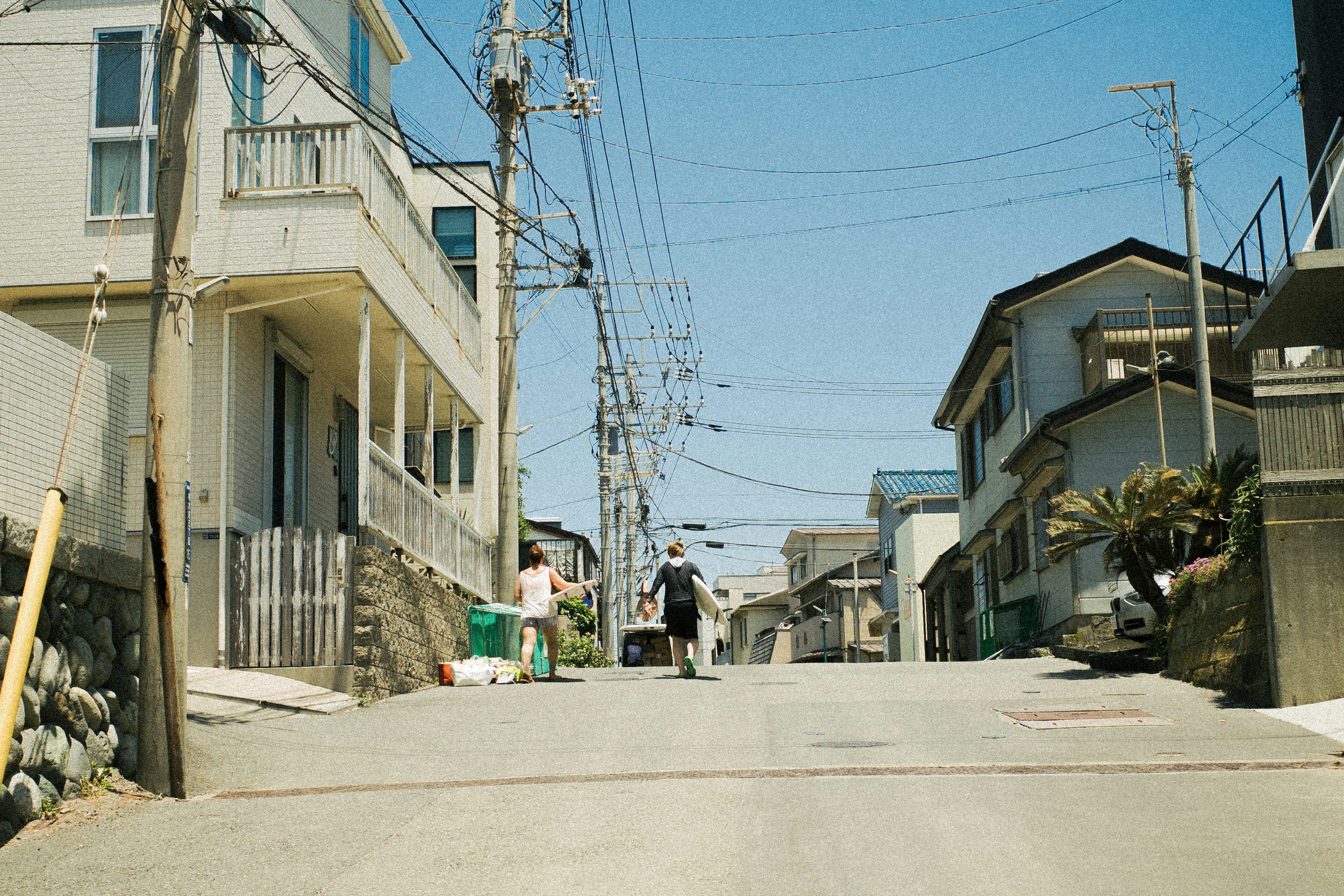 静かな住宅街の坂道を歩く人物と周囲の家々