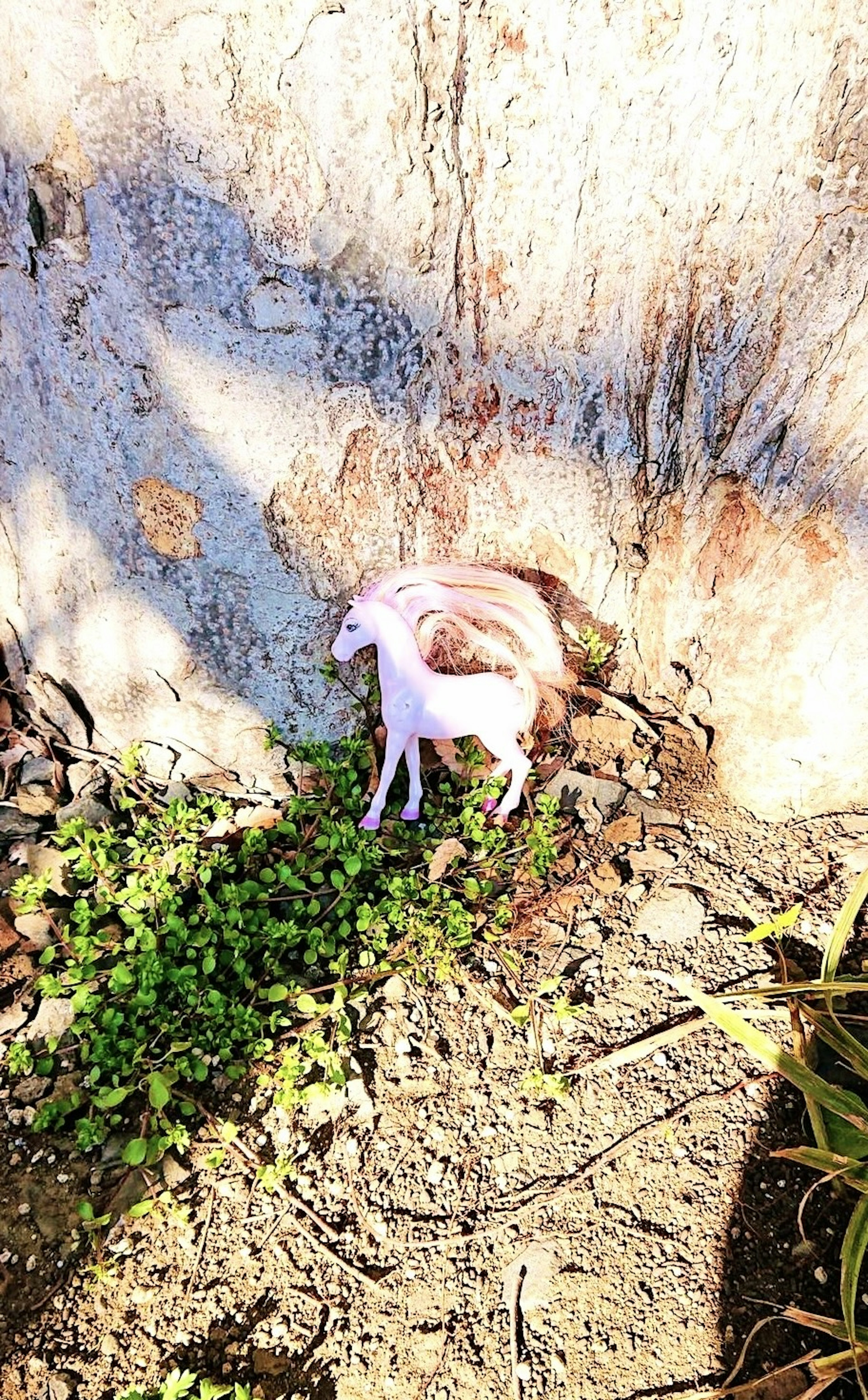 Una piccola figurina di cavallo rosa posizionata vicino a una roccia