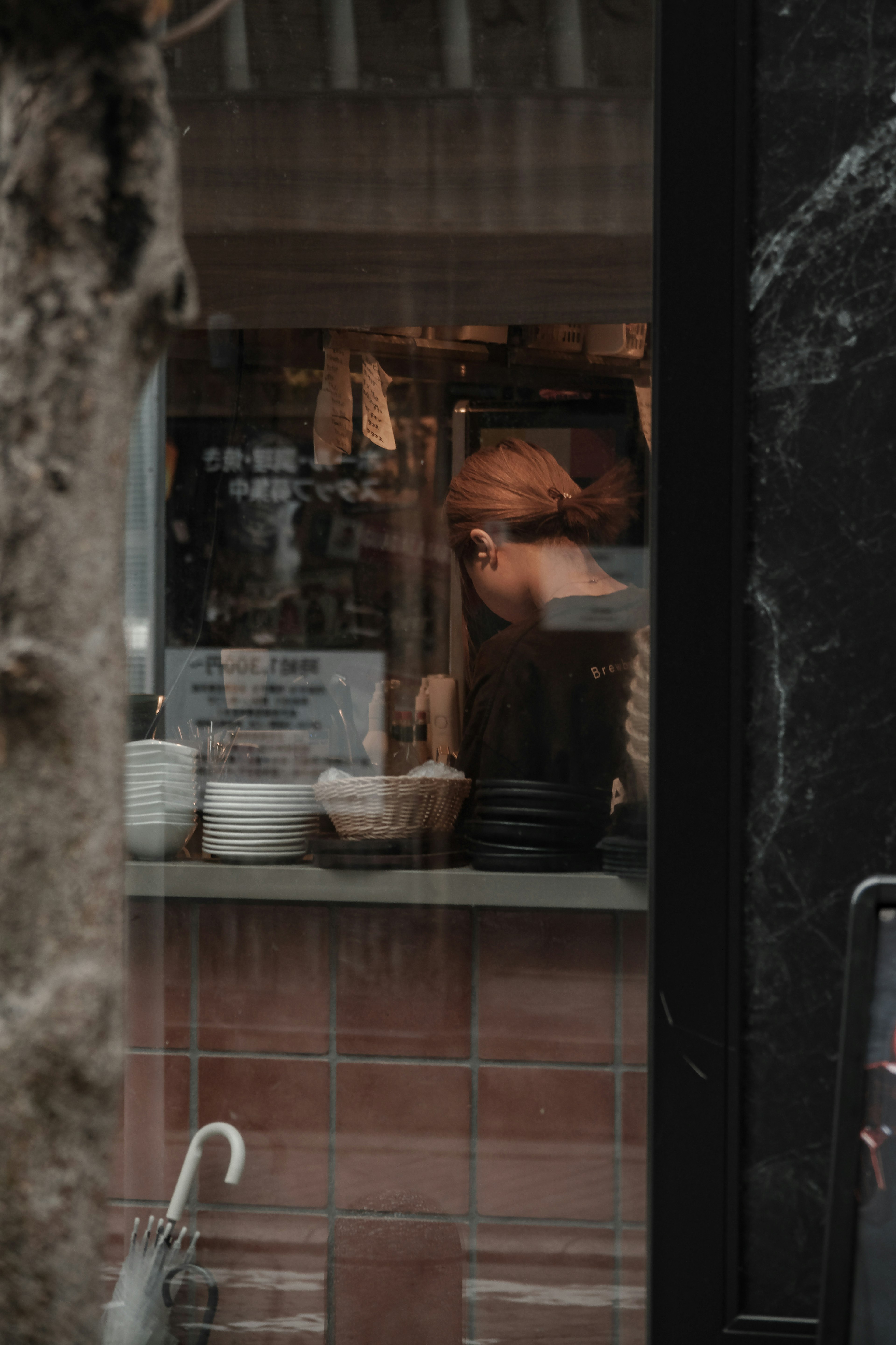 Vista a través de una ventana que muestra a un chef preparando comida en una cocina acogedora