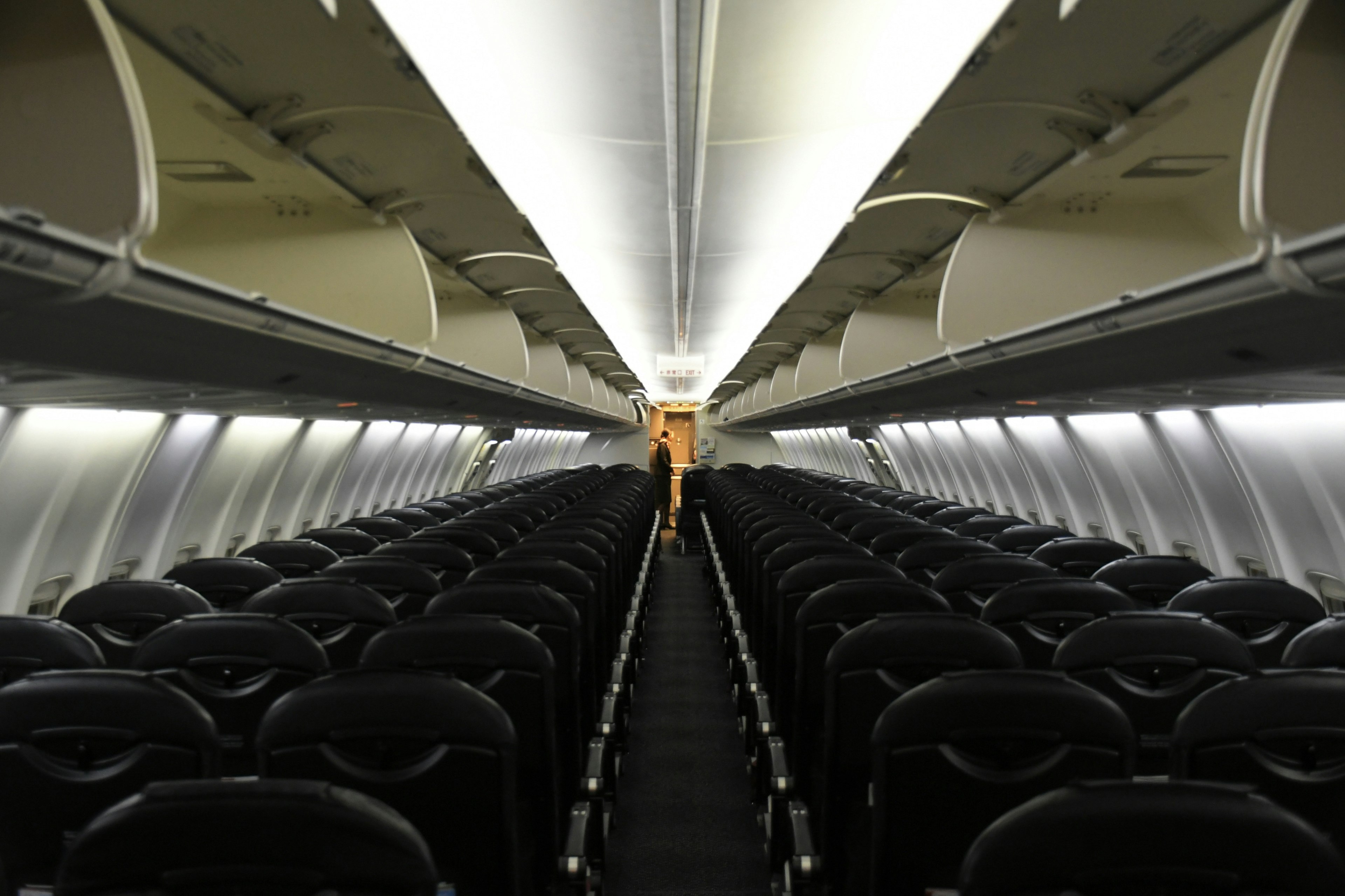 Interior of an empty airplane cabin featuring a long aisle and black seats