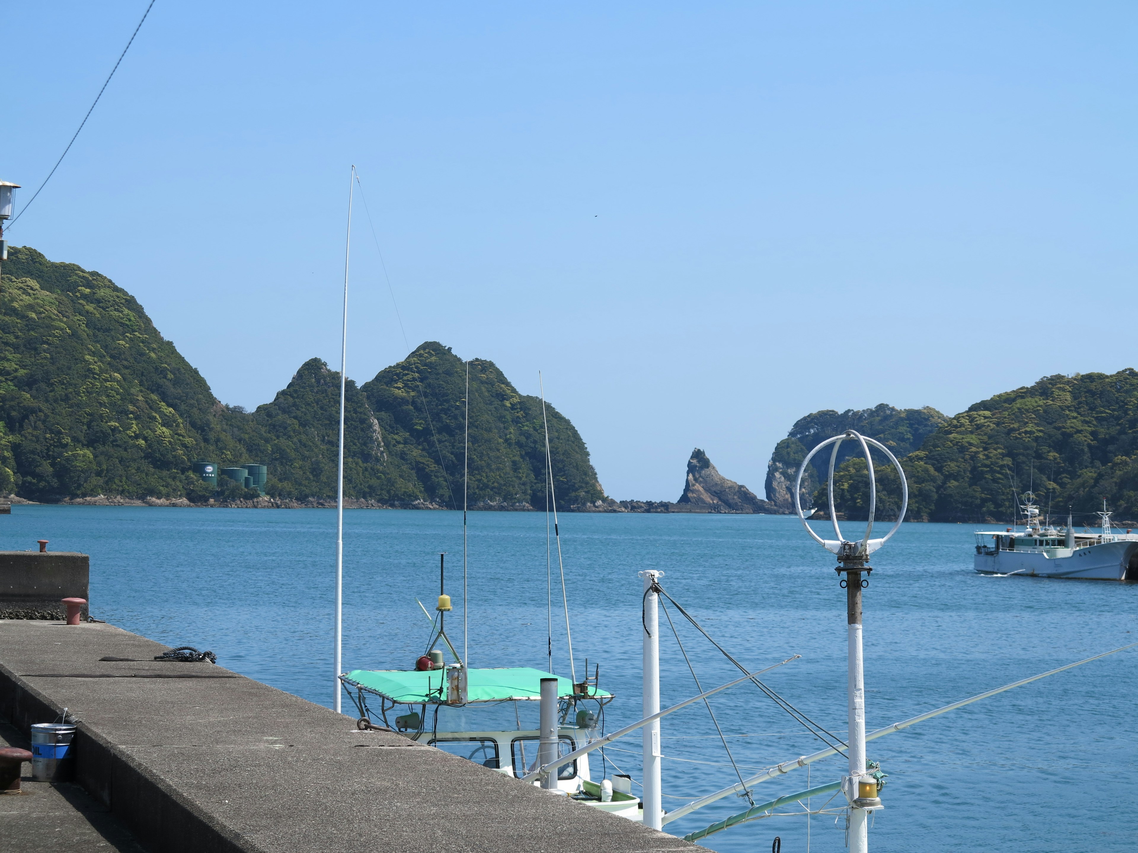 Harbor view with blue water and green mountains featuring boats and a radar antenna