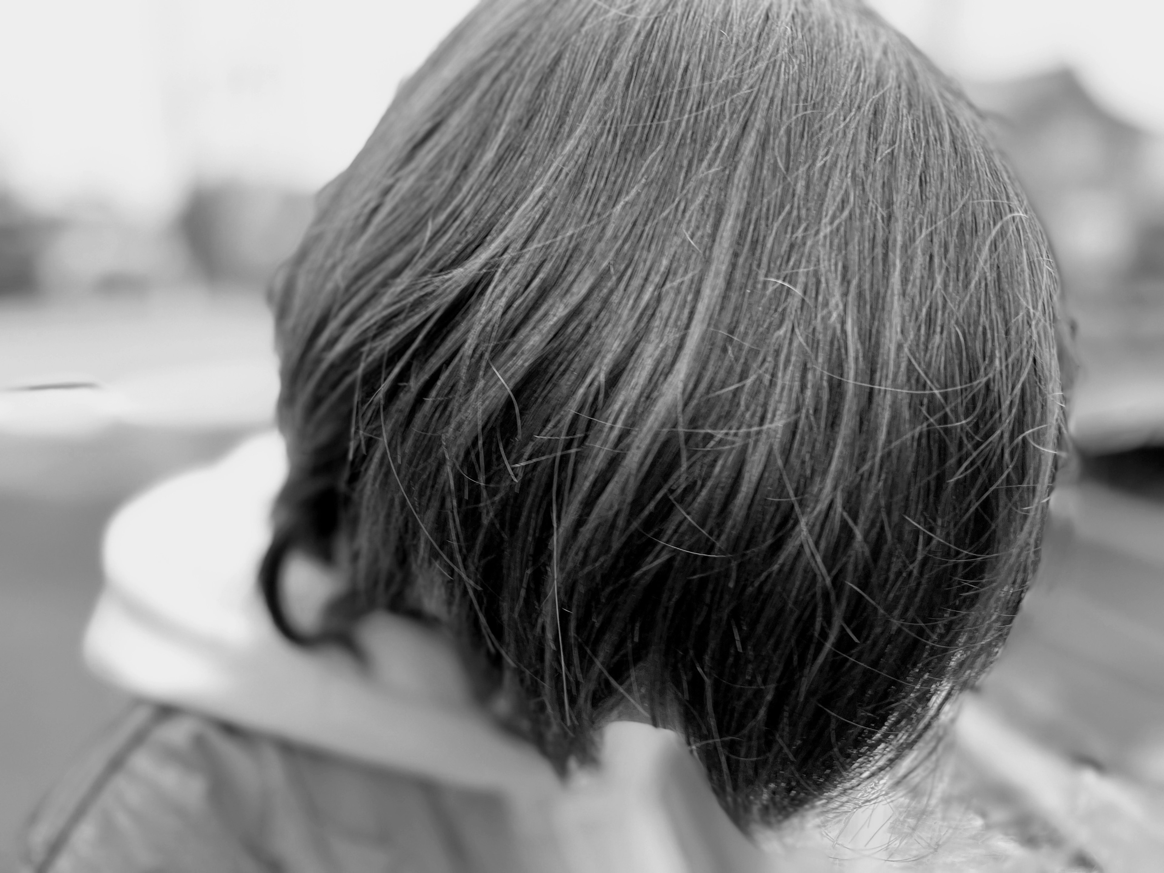 Black and white image of a person with distinctive hairstyle facing away