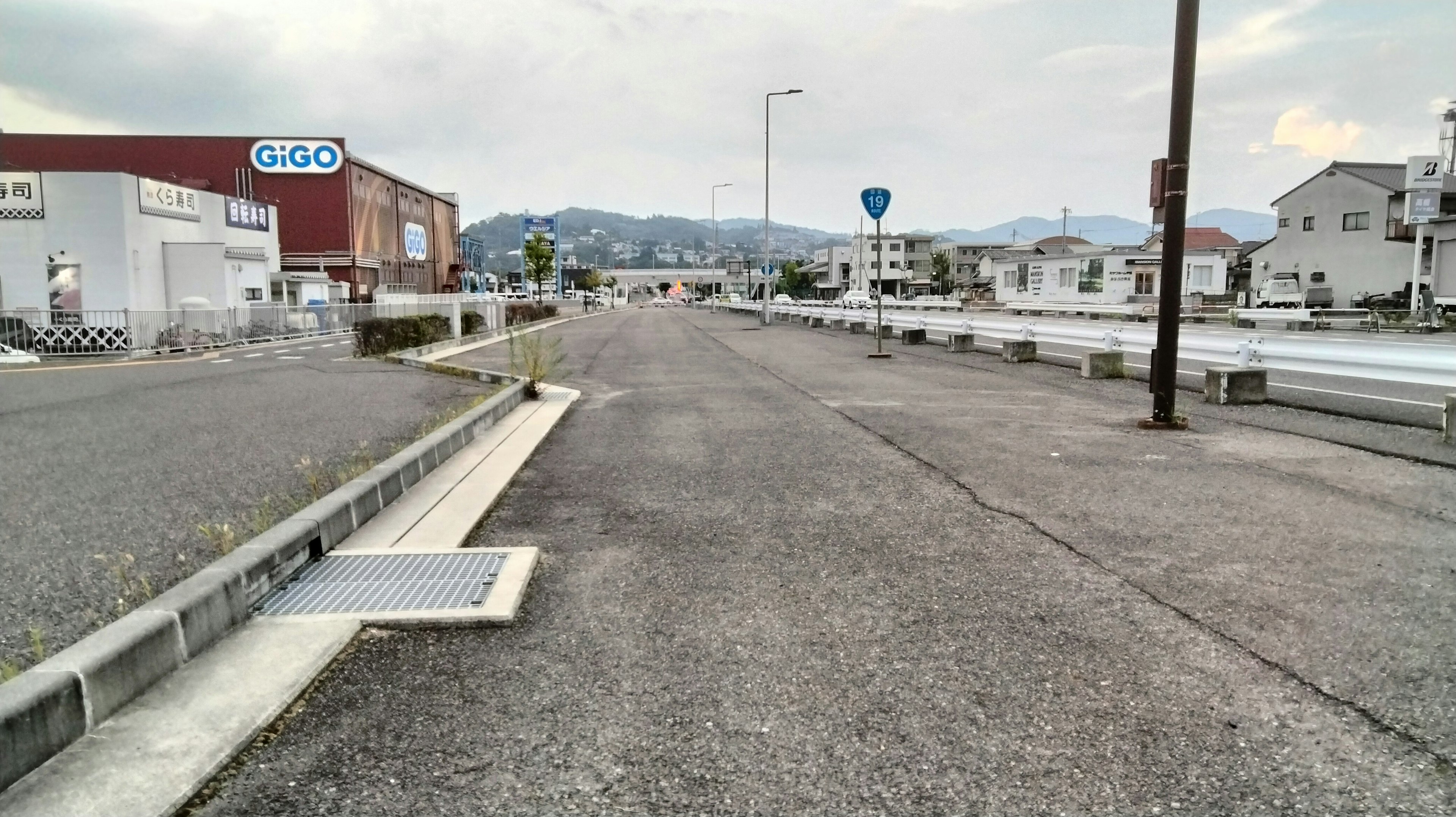 Amplia carretera con edificios alrededor y montañas al fondo