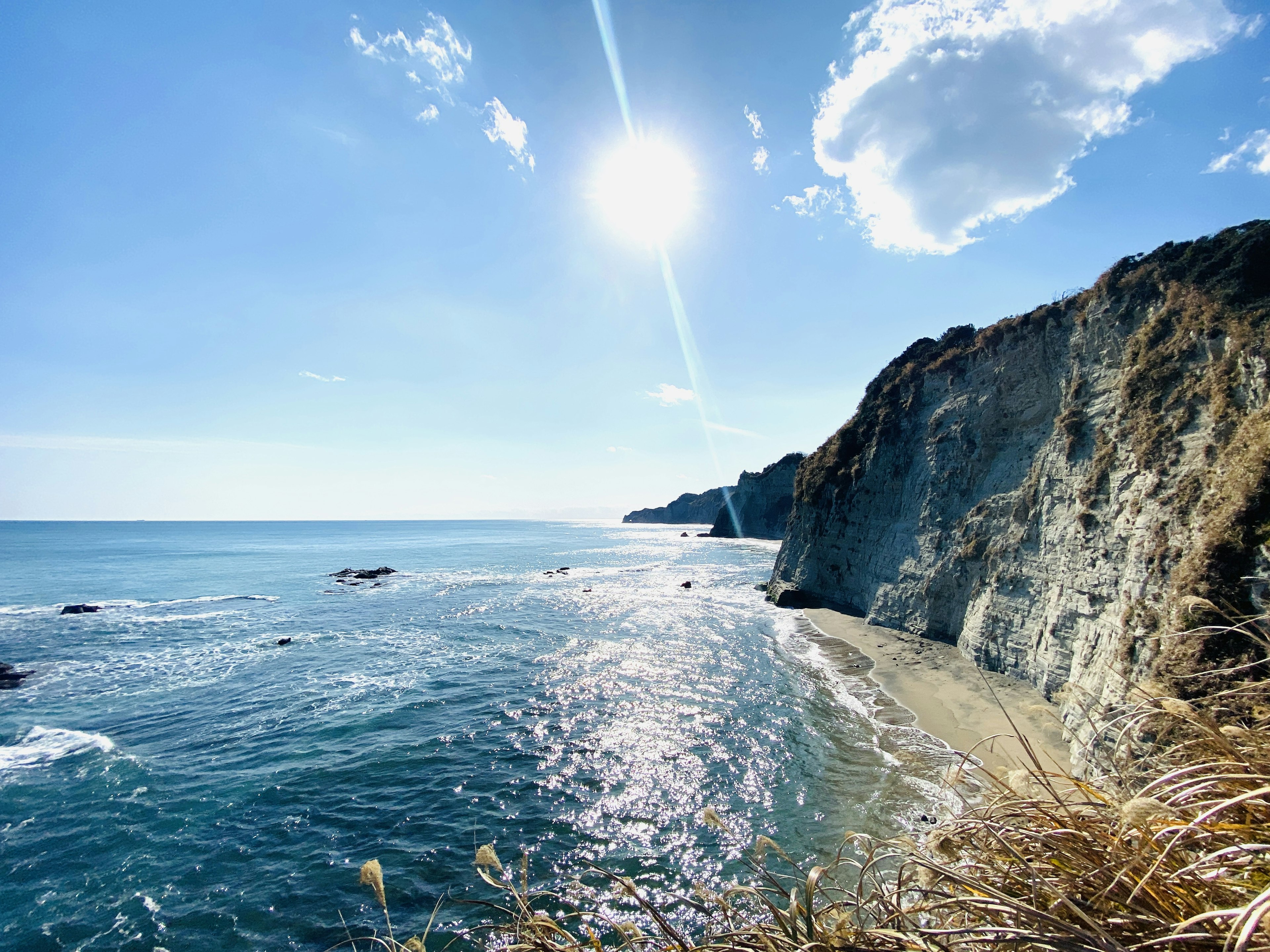 Scenic coastline featuring blue ocean and white cliffs bright sun in a clear blue sky with clouds