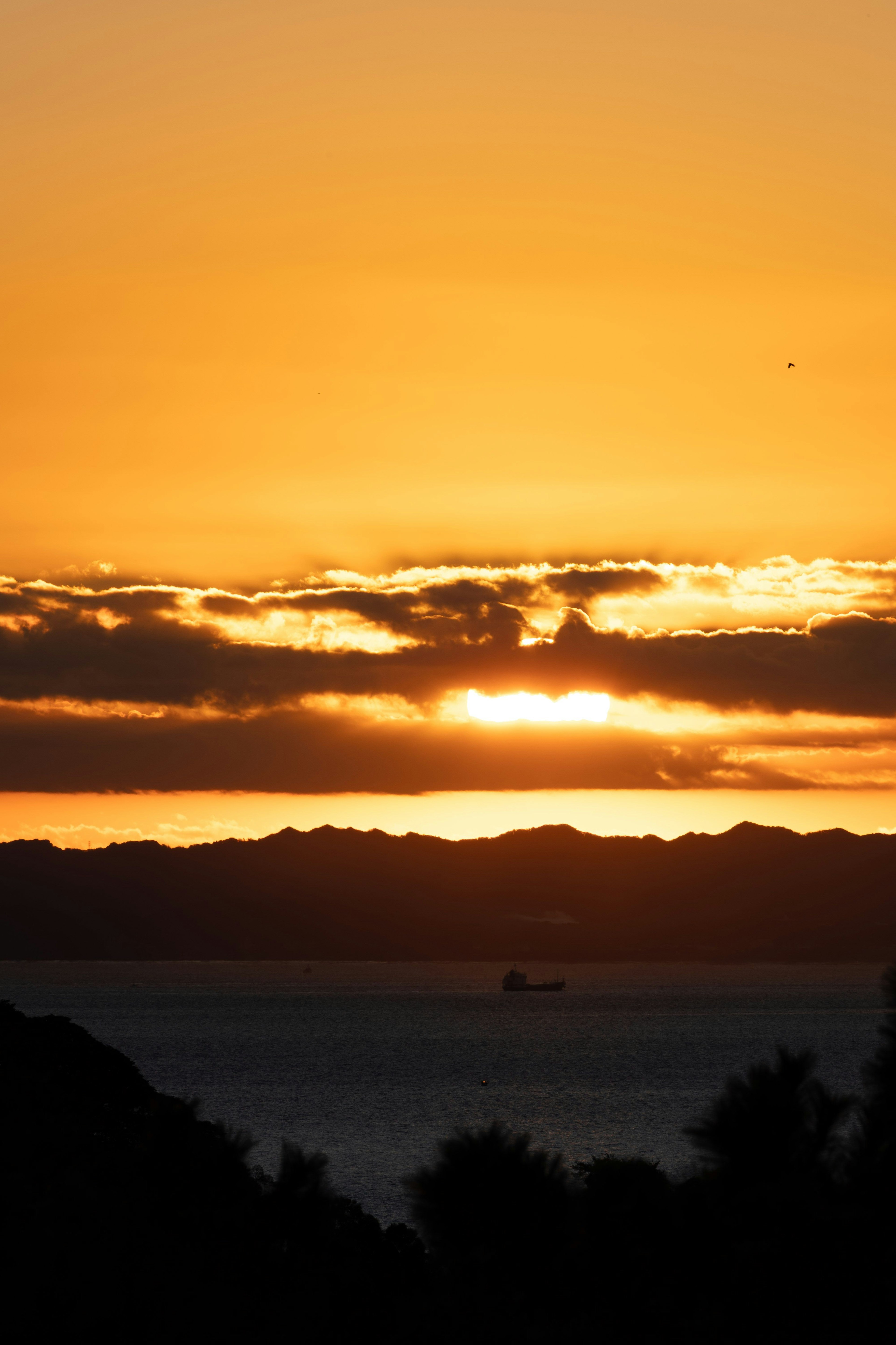 夕日が海に沈む美しい風景 山々と雲がオレンジ色に染まる