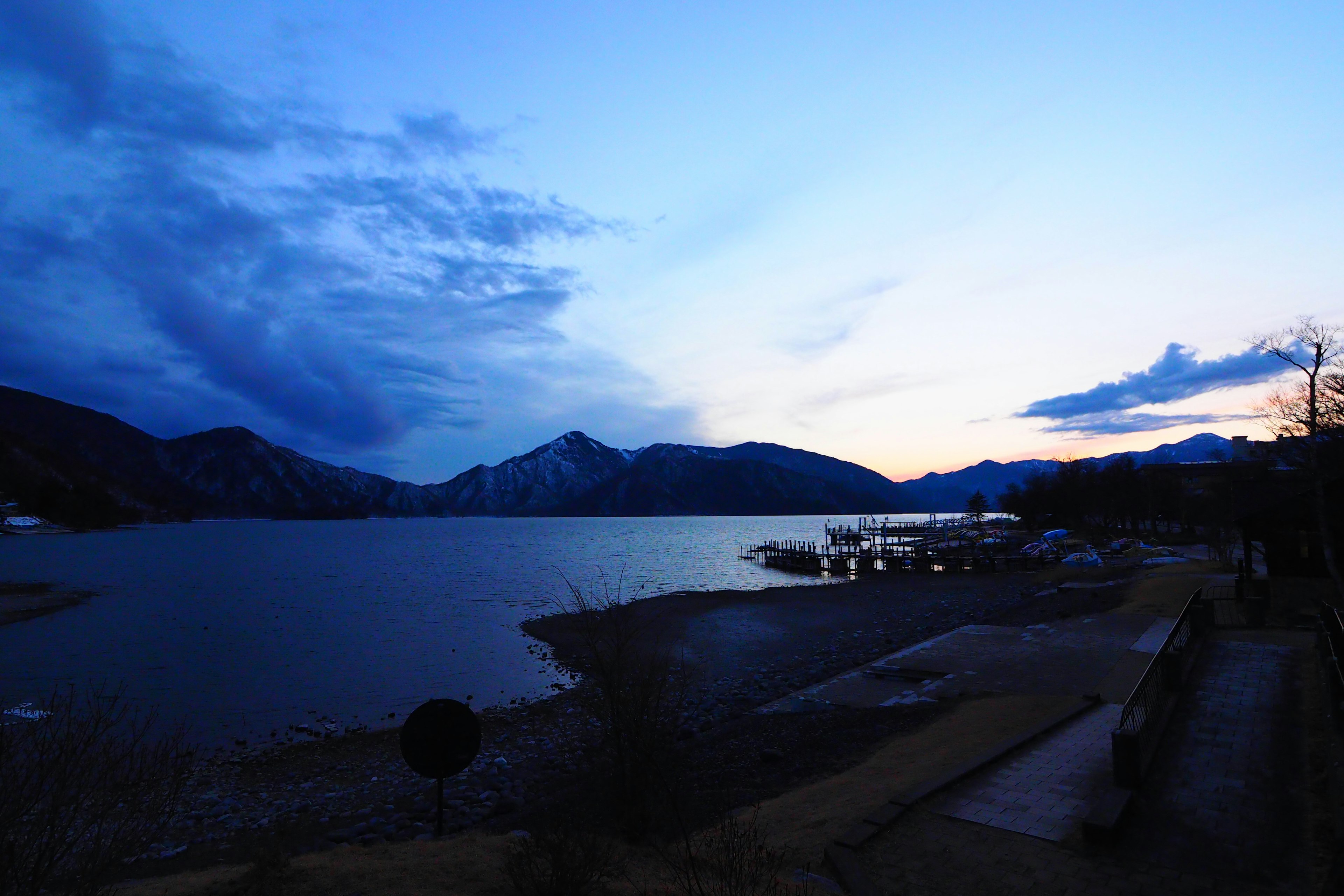 Twilight view of a lake and mountains Calm water surface with a blue sky