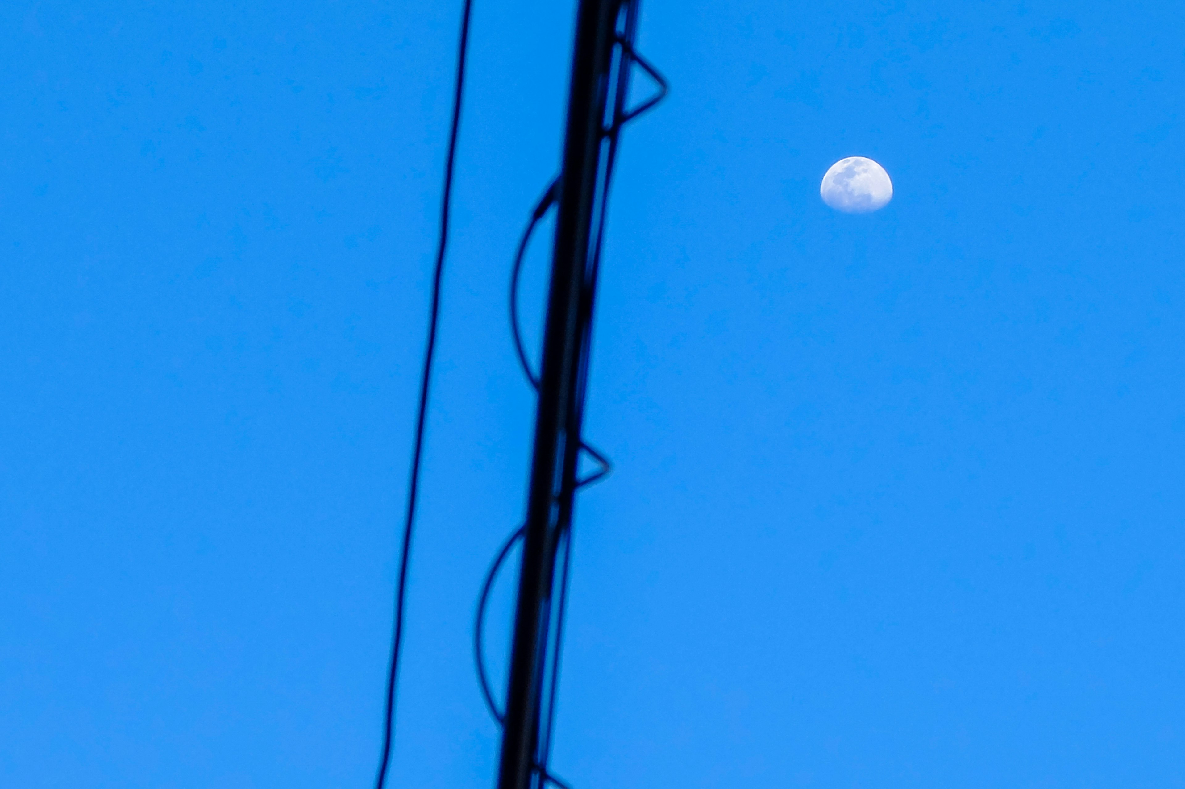 Mond im blauen Himmel mit Stromleitungen