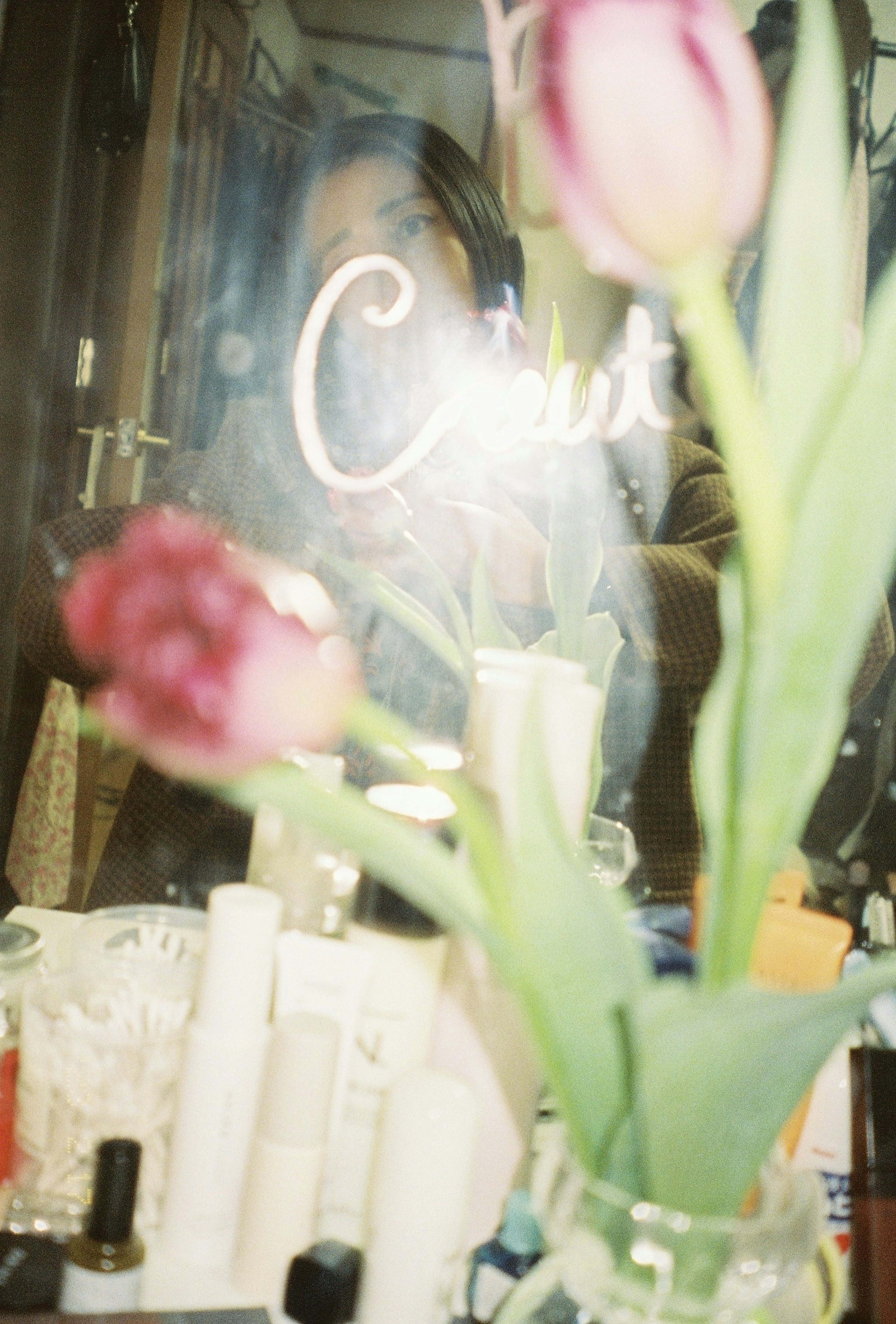 A photo featuring tulips and cosmetics reflected in a mirror