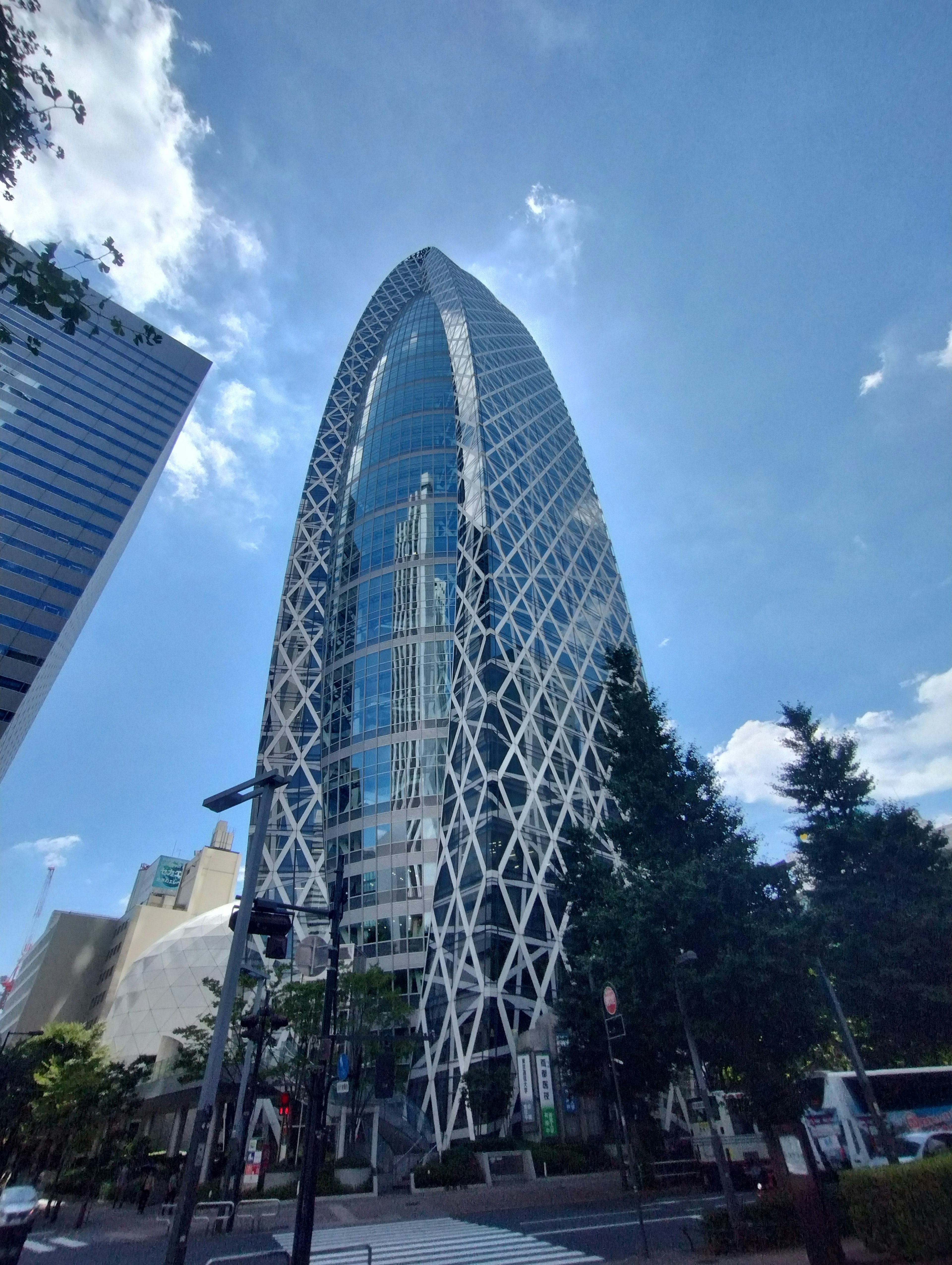 新宿の特徴的な建物、ガラスと金属のファサード、青空と雲の背景