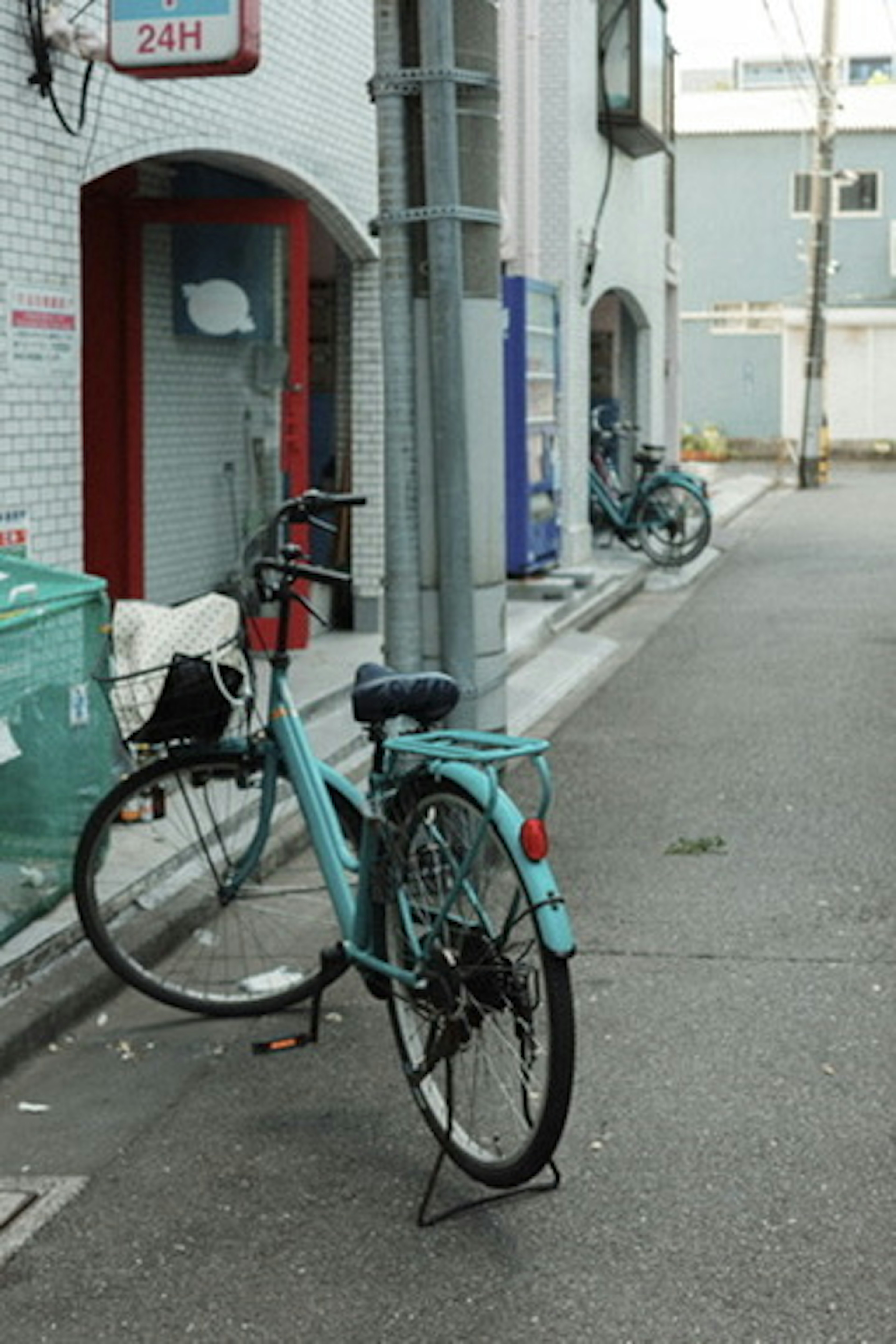 A blue bicycle parked on a narrow street with buildings in the background