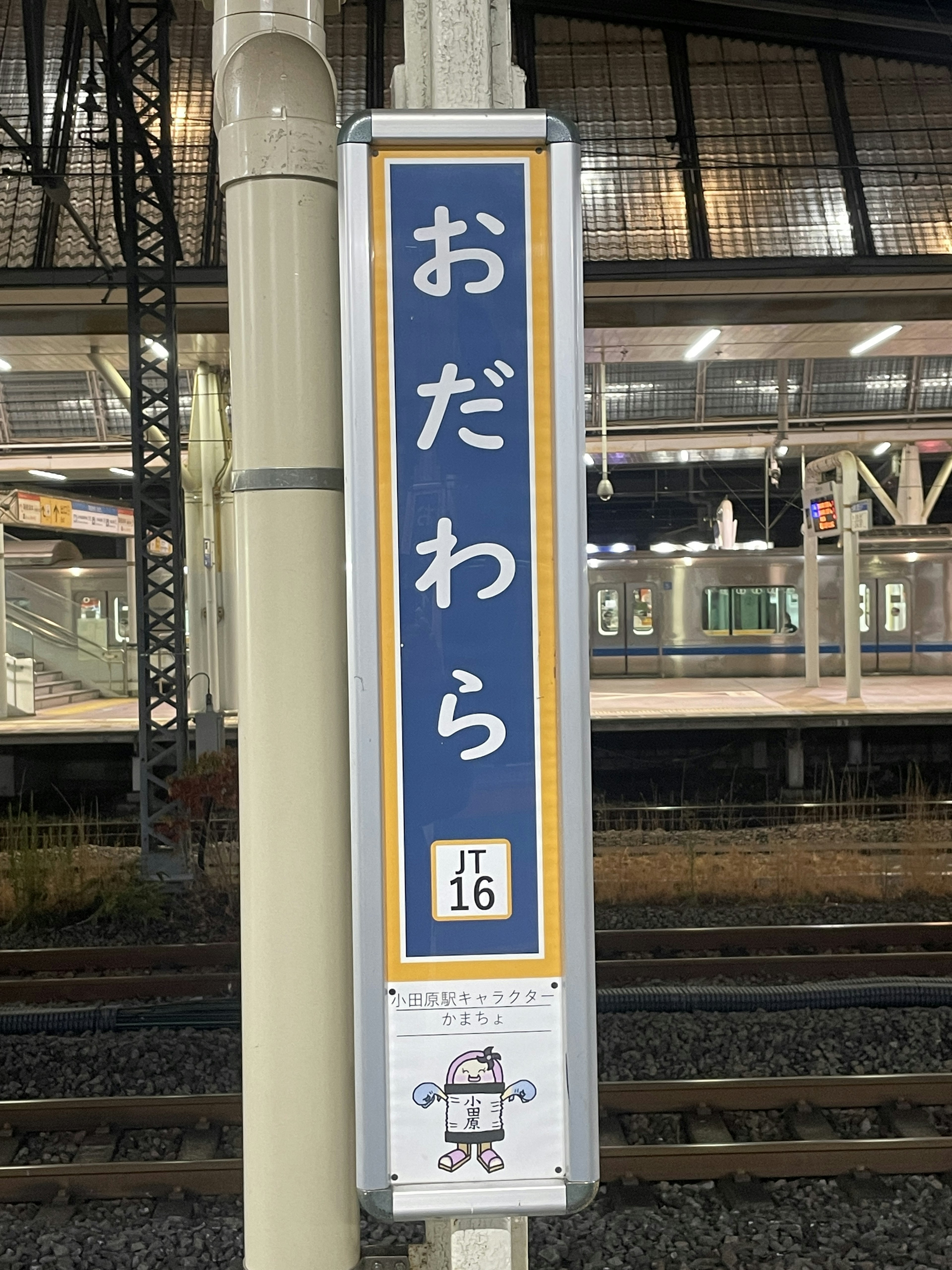 おだわら駅の表示看板と背景に列車