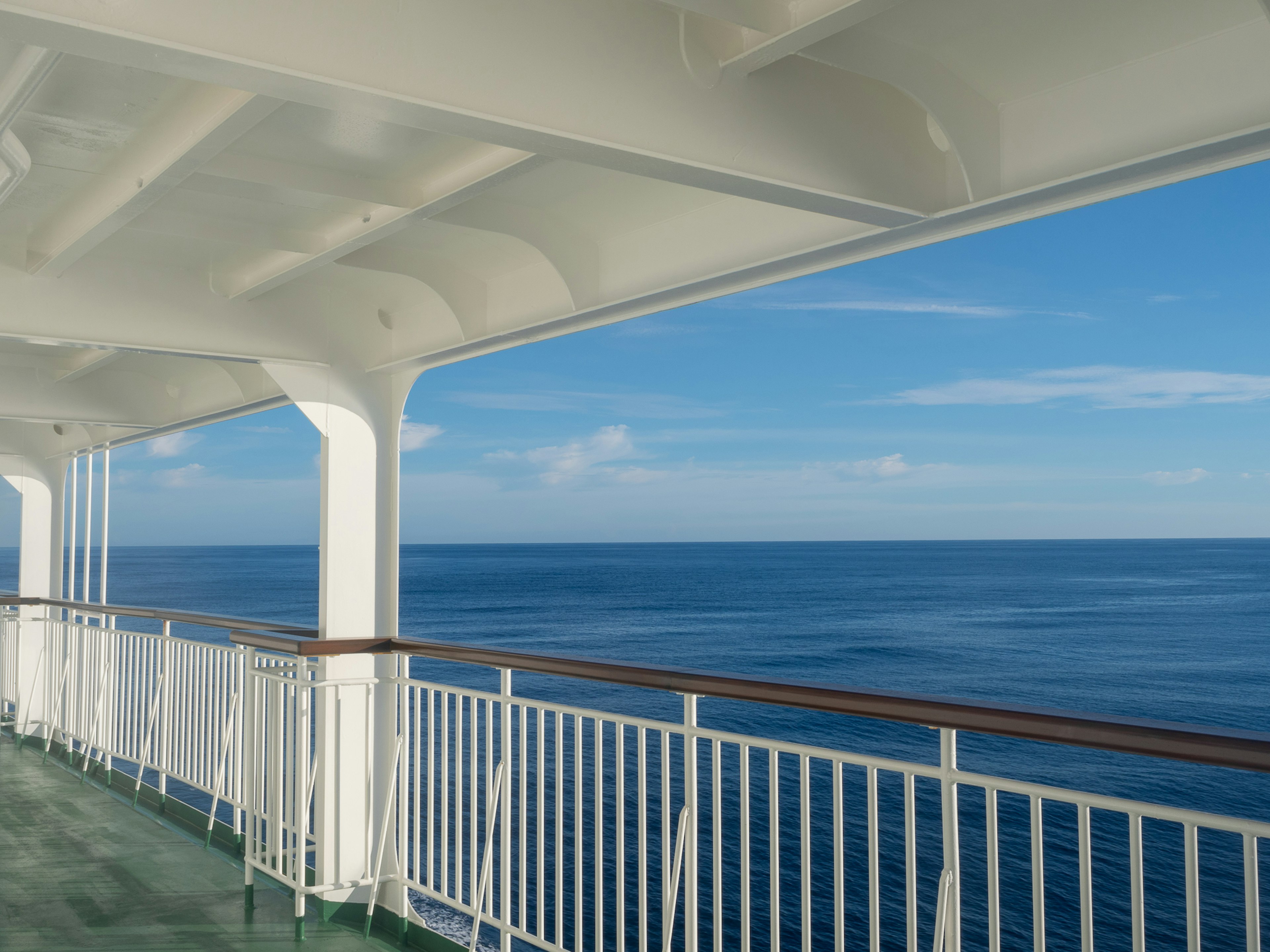 Deck eines Kreuzfahrtschiffes mit Blick auf den ruhigen Ozean und den klaren blauen Himmel