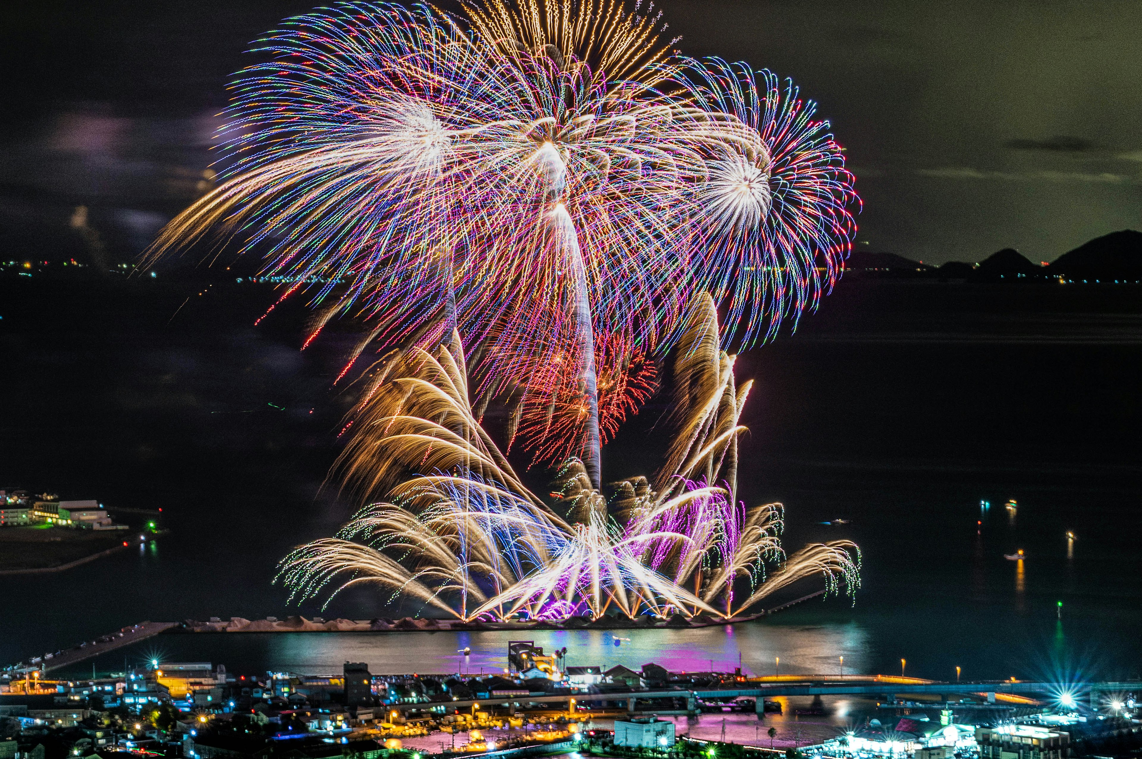 Vibrant fireworks display illuminating the night sky over the sea